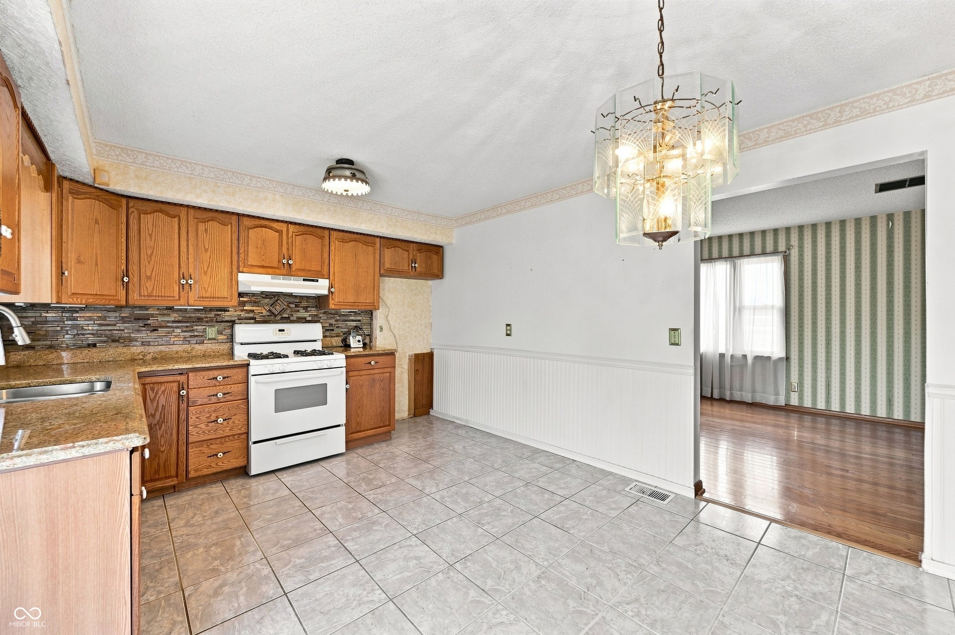 14 x 11 Kitchen with tile floors, updated cabinets, granite counter tops, glass tile splashback plus space for table and chairs with patio access.