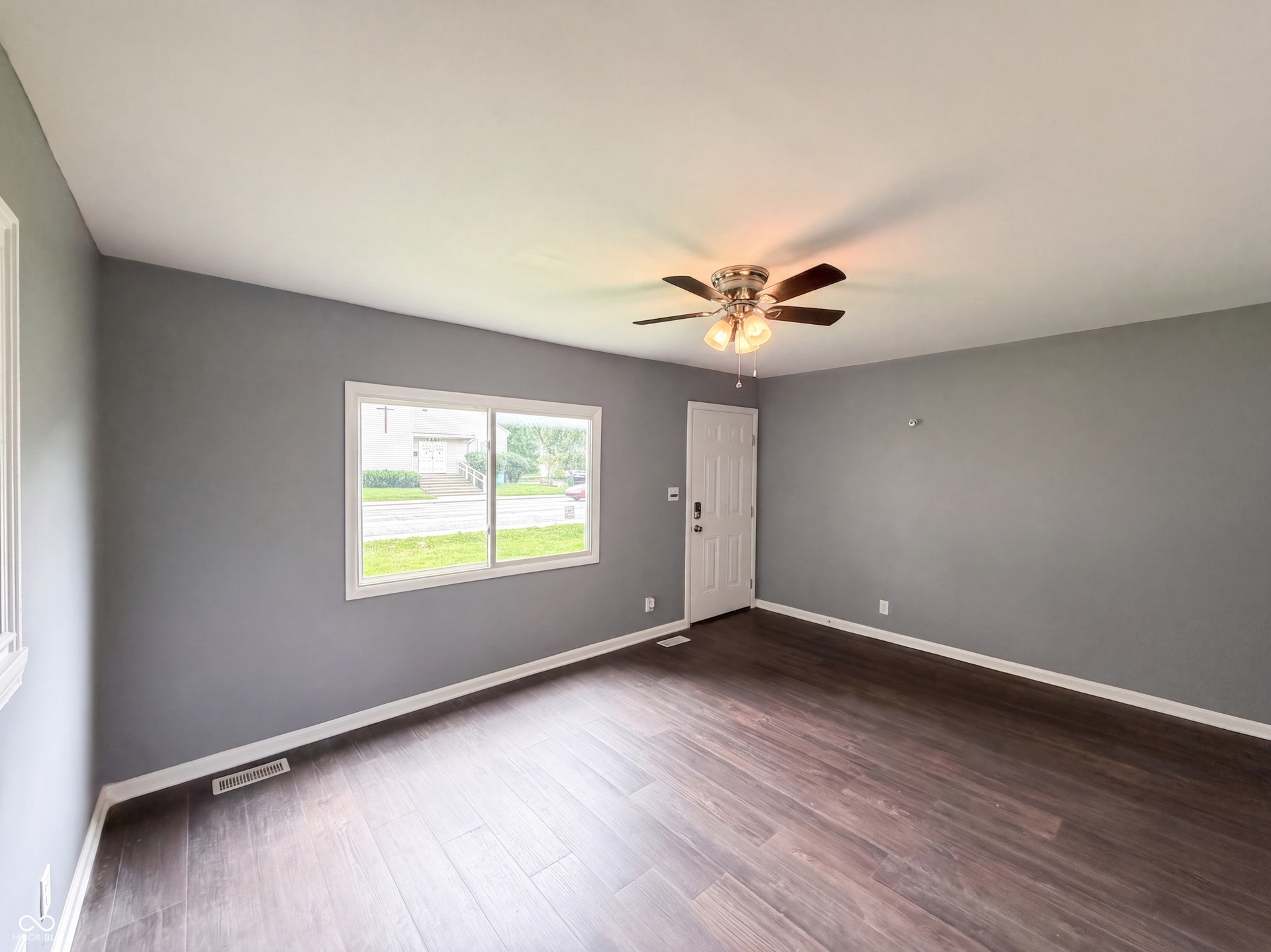 Wood-finish flooring, neutral gray walls, and white trim