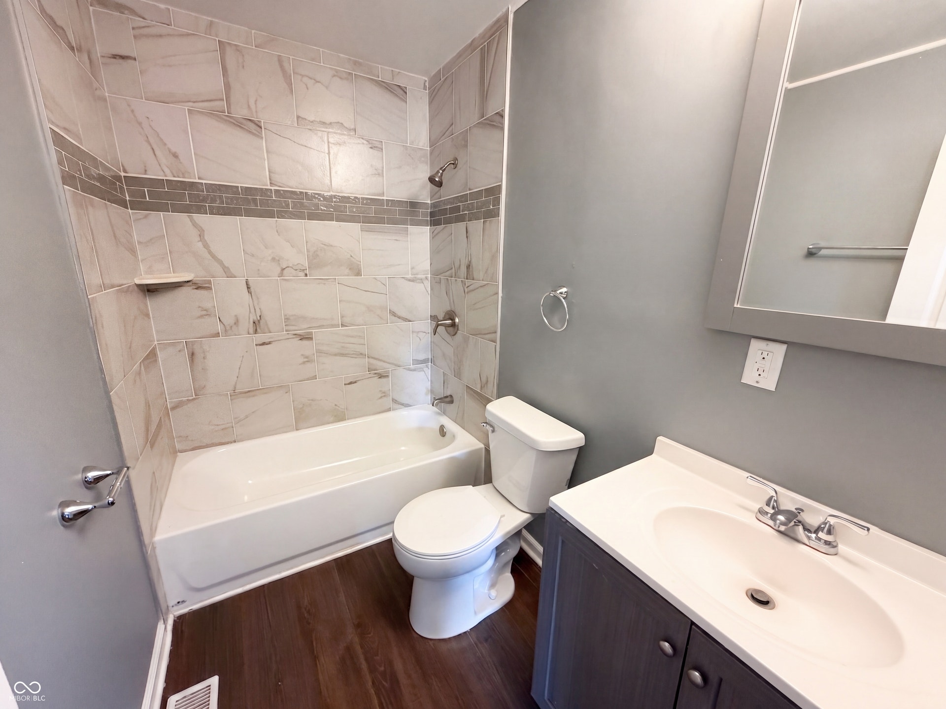Tub and shower combination with tile surround, decorative tile accent band, and built-in shelf