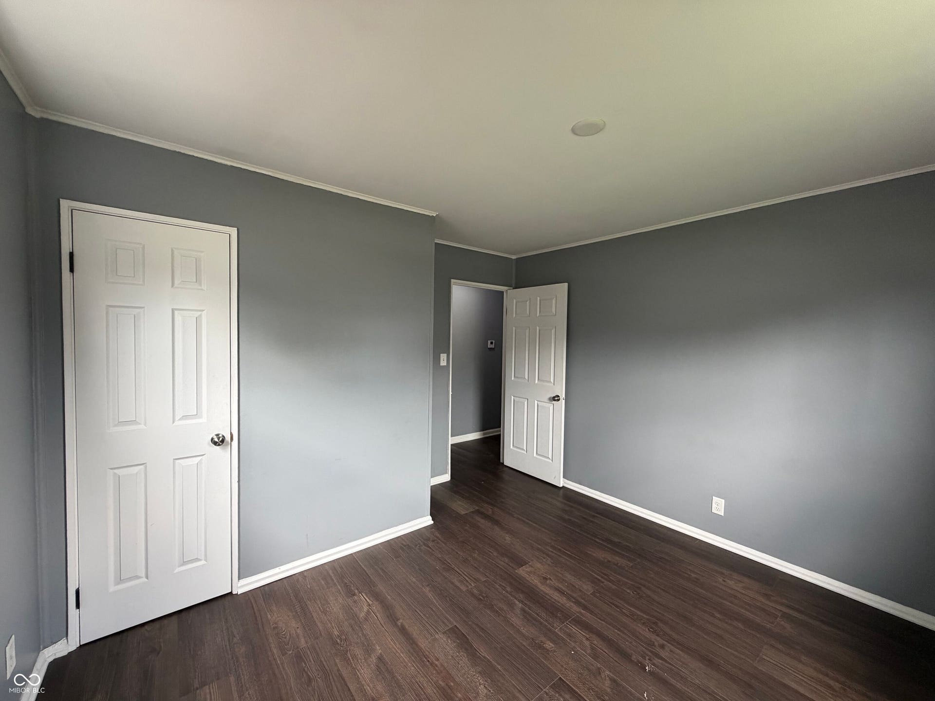 Wood-finish flooring, recessed lighting, crown molding, paneled doors, and gray wall finishes
