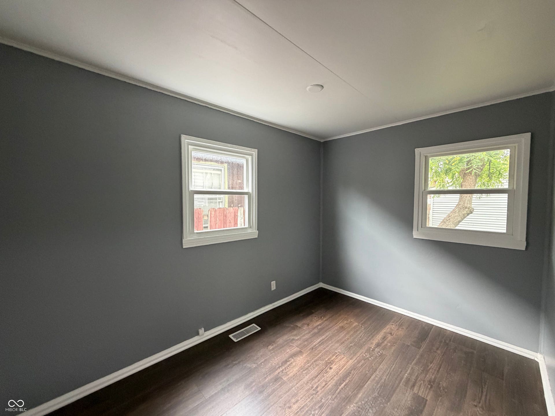 Neutral gray wall finishes, wood-finish flooring, white window trim, and white crown molding