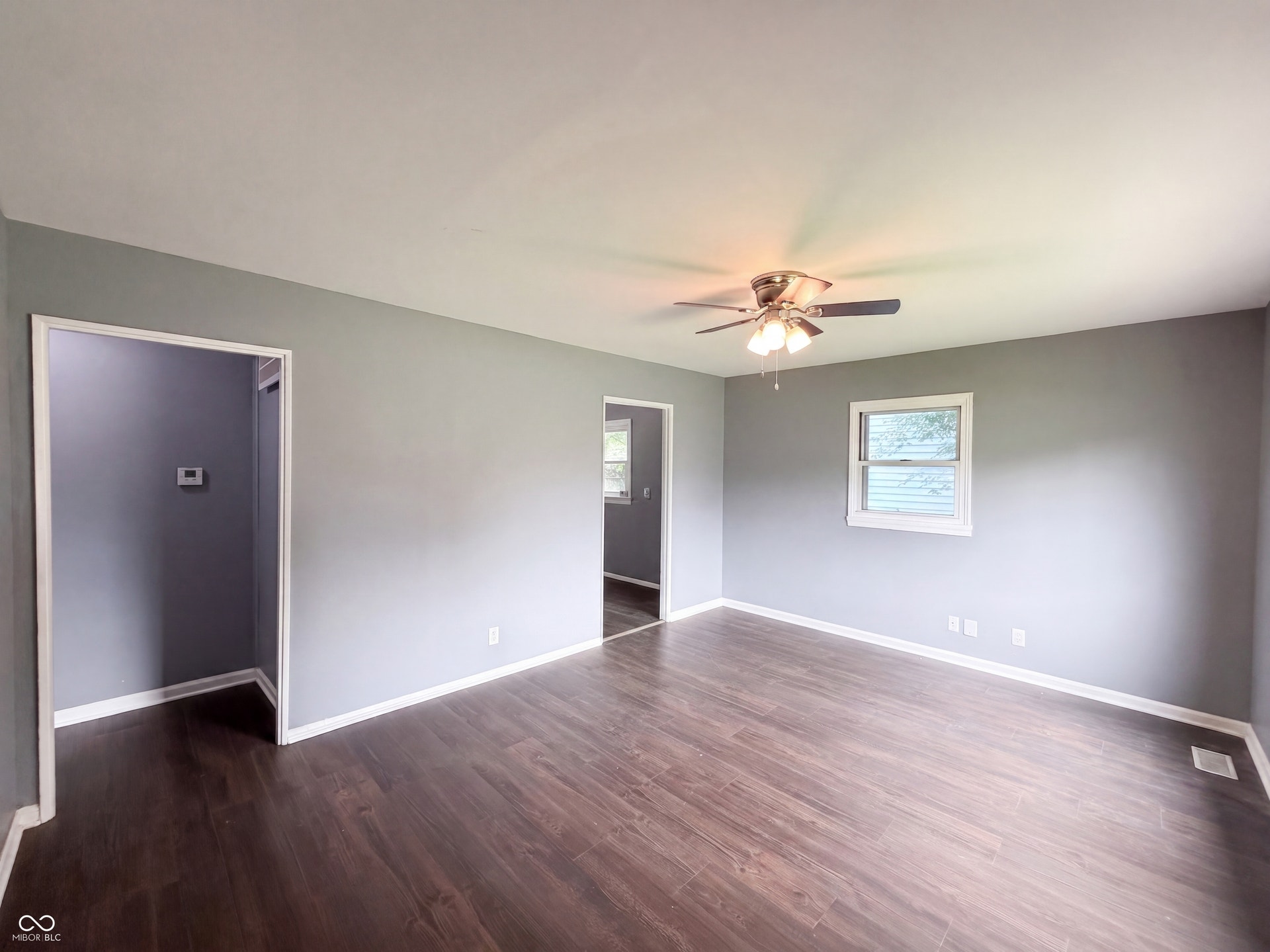 Wood-finish flooring, neutral gray wall tones, and a ceiling fan with integrated lighting