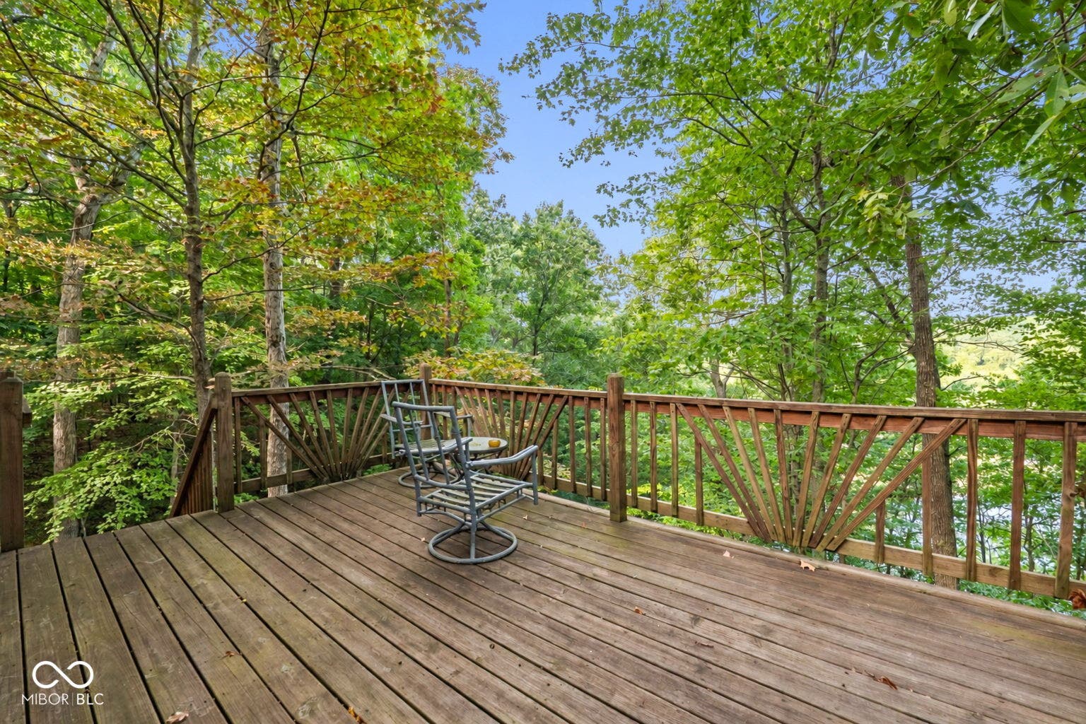 Expansive wood deck with a perimeter wood railing and natural tree canopy