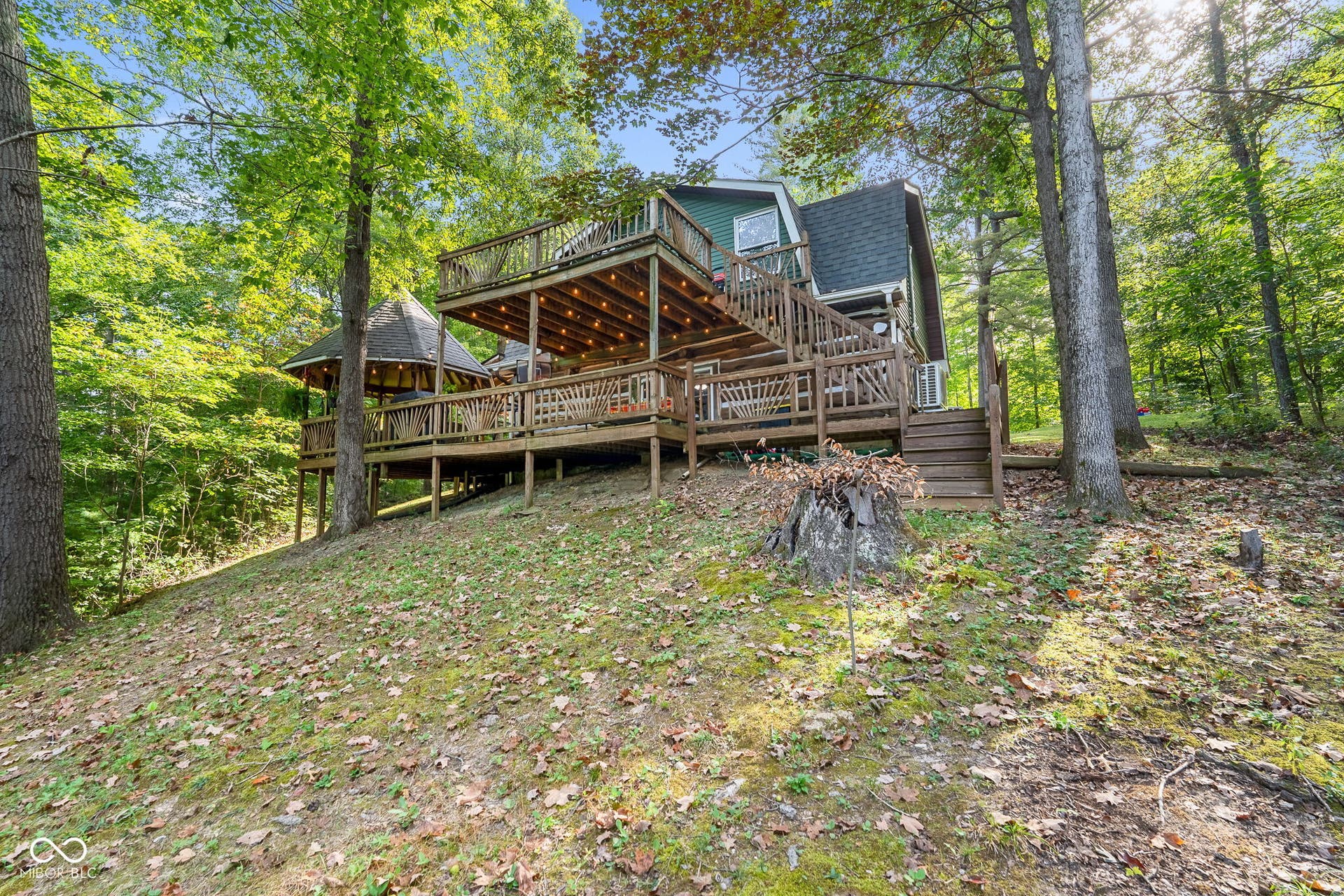 Multi-level wood decking featuring a gazebo, string lighting, and wood railings