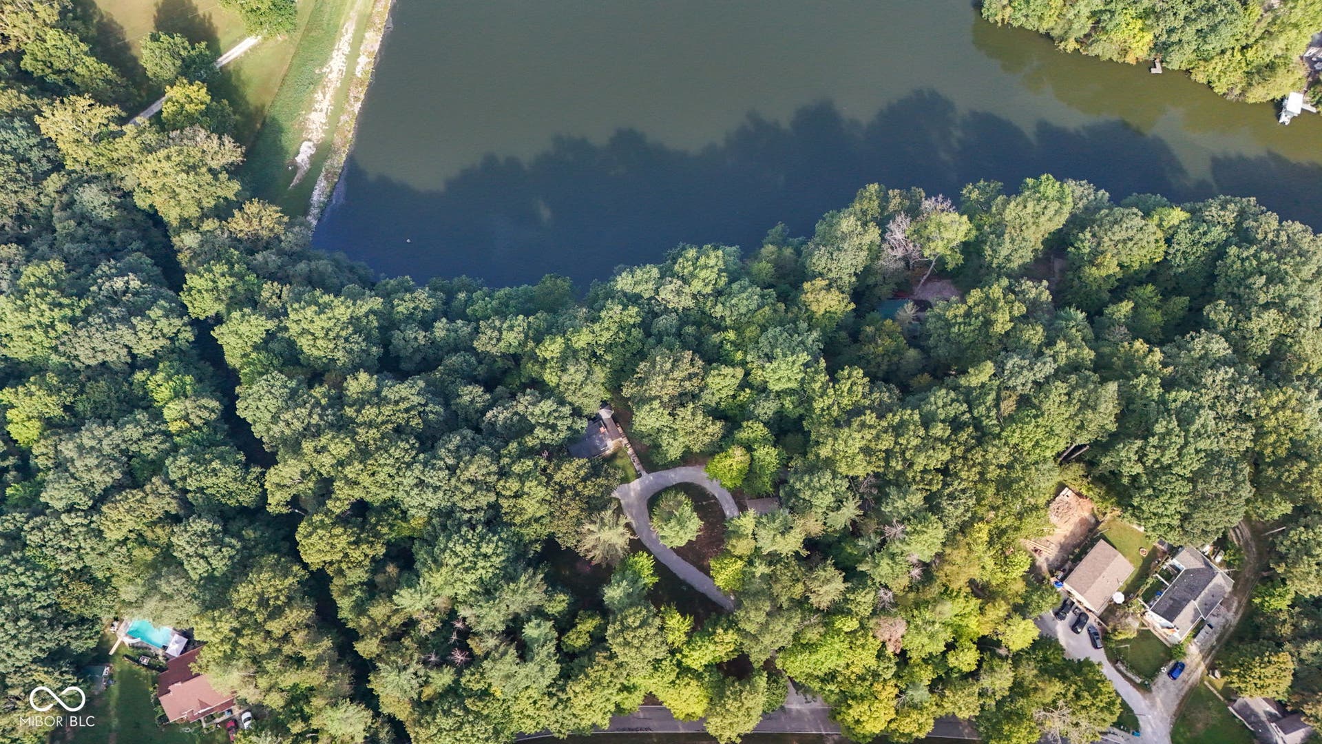 Expansive natural area featuring abundant mature trees and a tranquil body of water