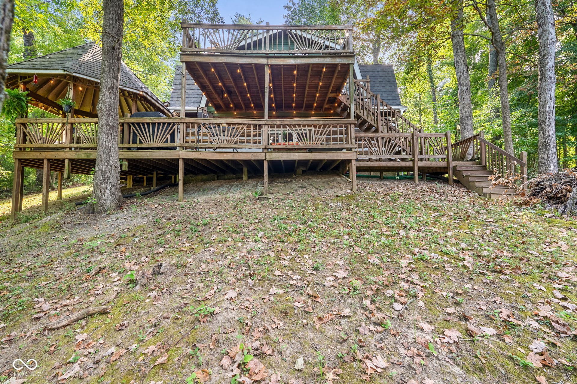 Multi-level wood deck with decorative railings, covered patio area, and upper-level sun deck