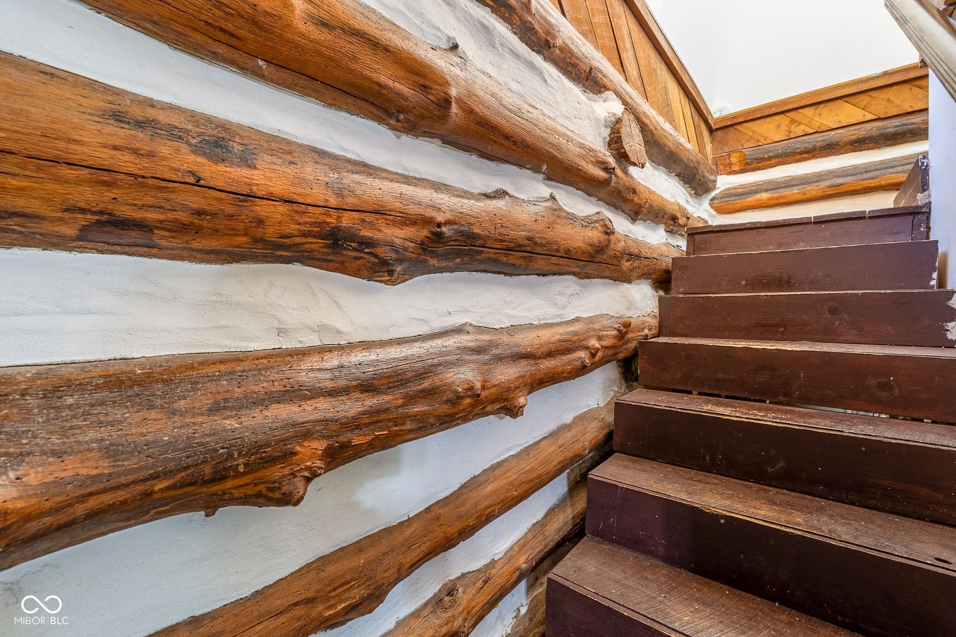 Staircase featuring wood steps, wood paneling, and log wall construction