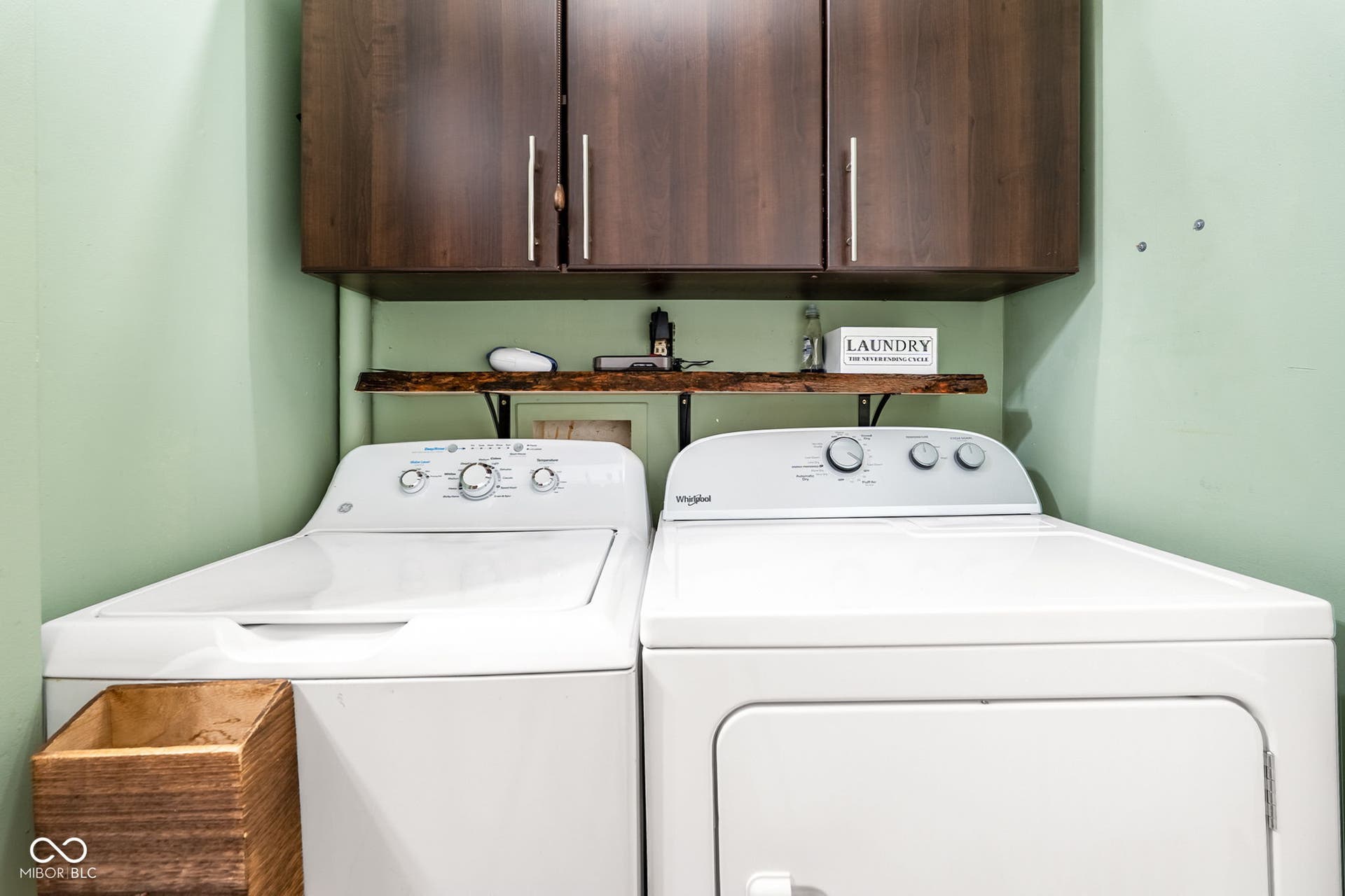 Built-in cabinetry with modern pulls, wood-finish shelving, and light green wall paint