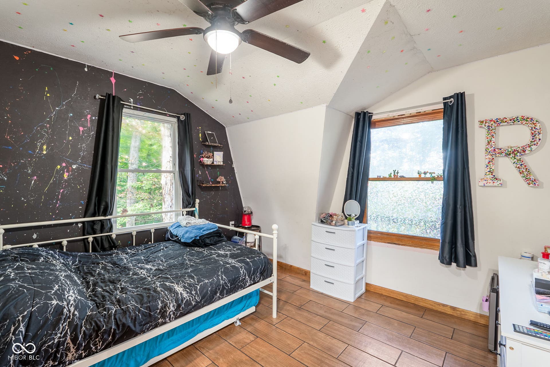 Wood-finish flooring, two windows with wood trim, ceiling fan with integrated lighting, and sloped ceilings