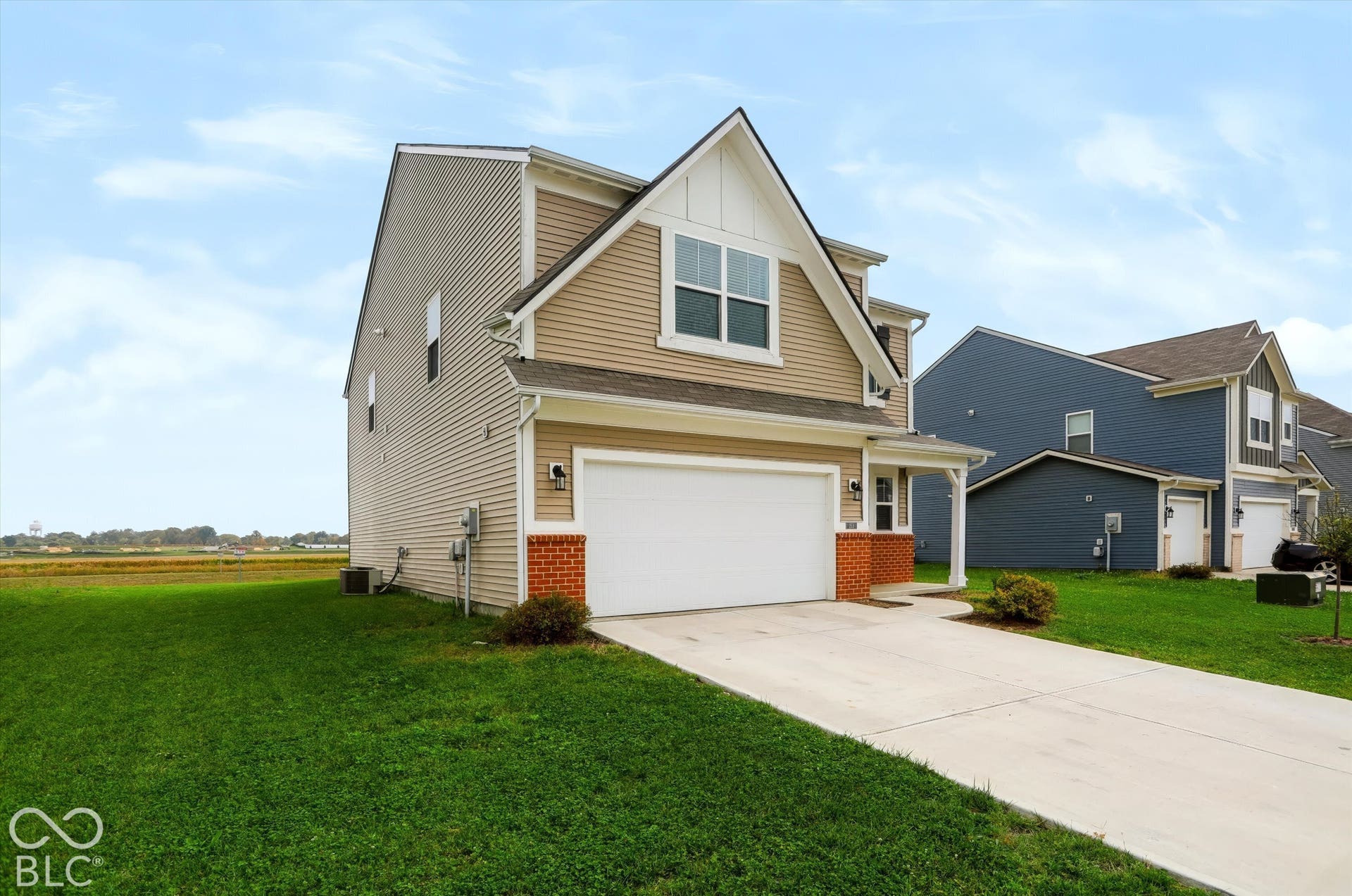 Two-story residence featuring horizontal lap siding, a front-facing gable with board-and-batten detailing, brick veneer accents, a concrete driveway, and an attached two-car garage
