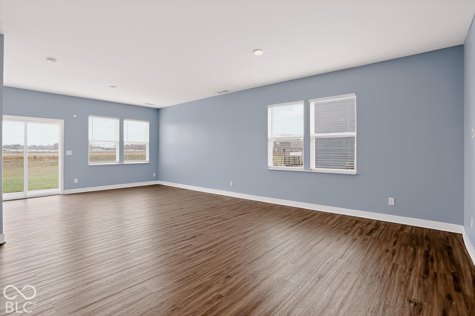 Expansive room featuring wood-finish flooring, recessed lighting, double-pane windows, and a sliding glass door