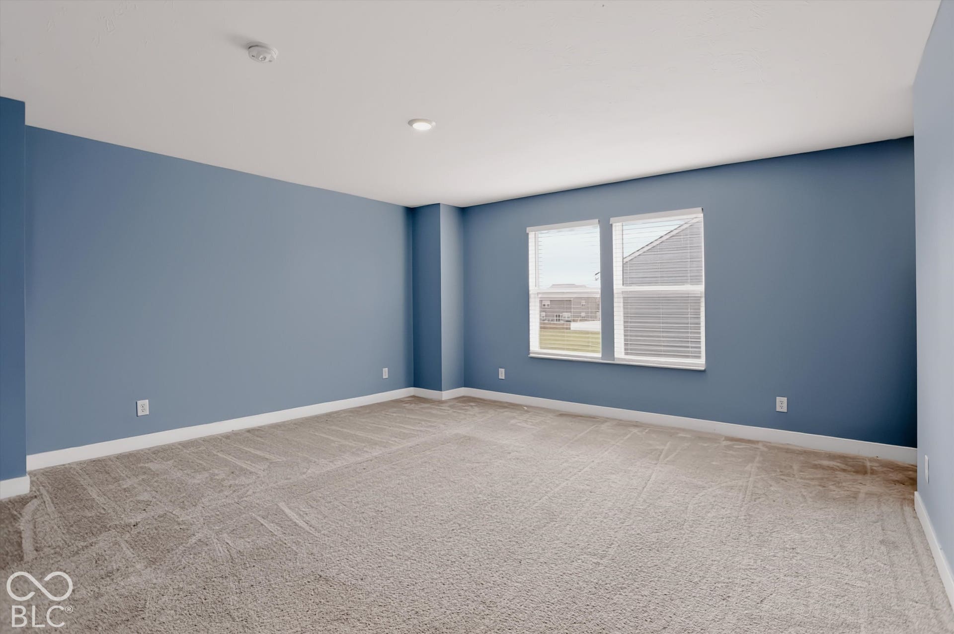Spacious room featuring neutral carpeting, recessed ceiling lighting, and dual-pane windows
