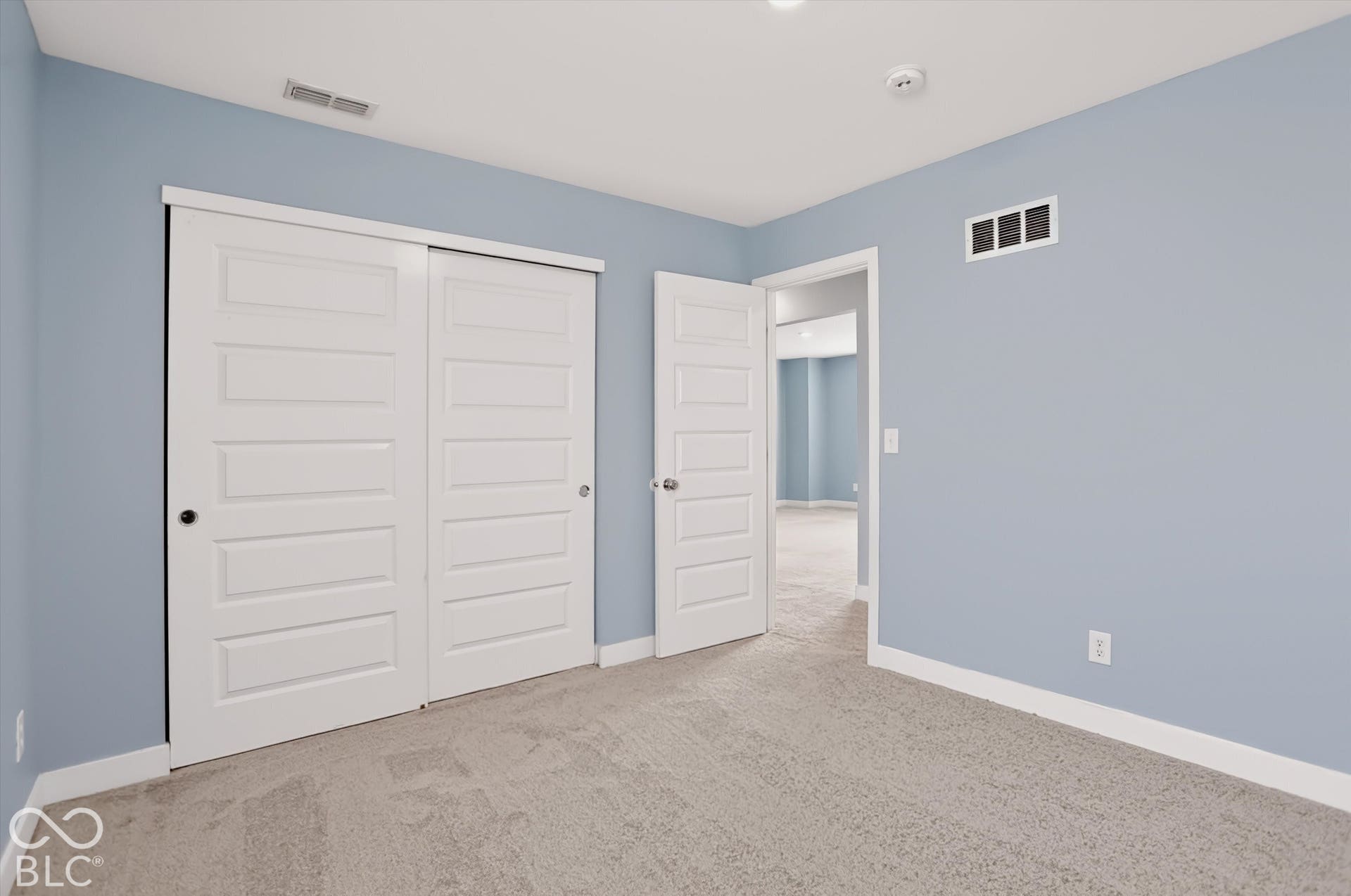 Neutral-toned wall paint, neutral carpeting, sliding bypass closet doors, and six-panel interior doors