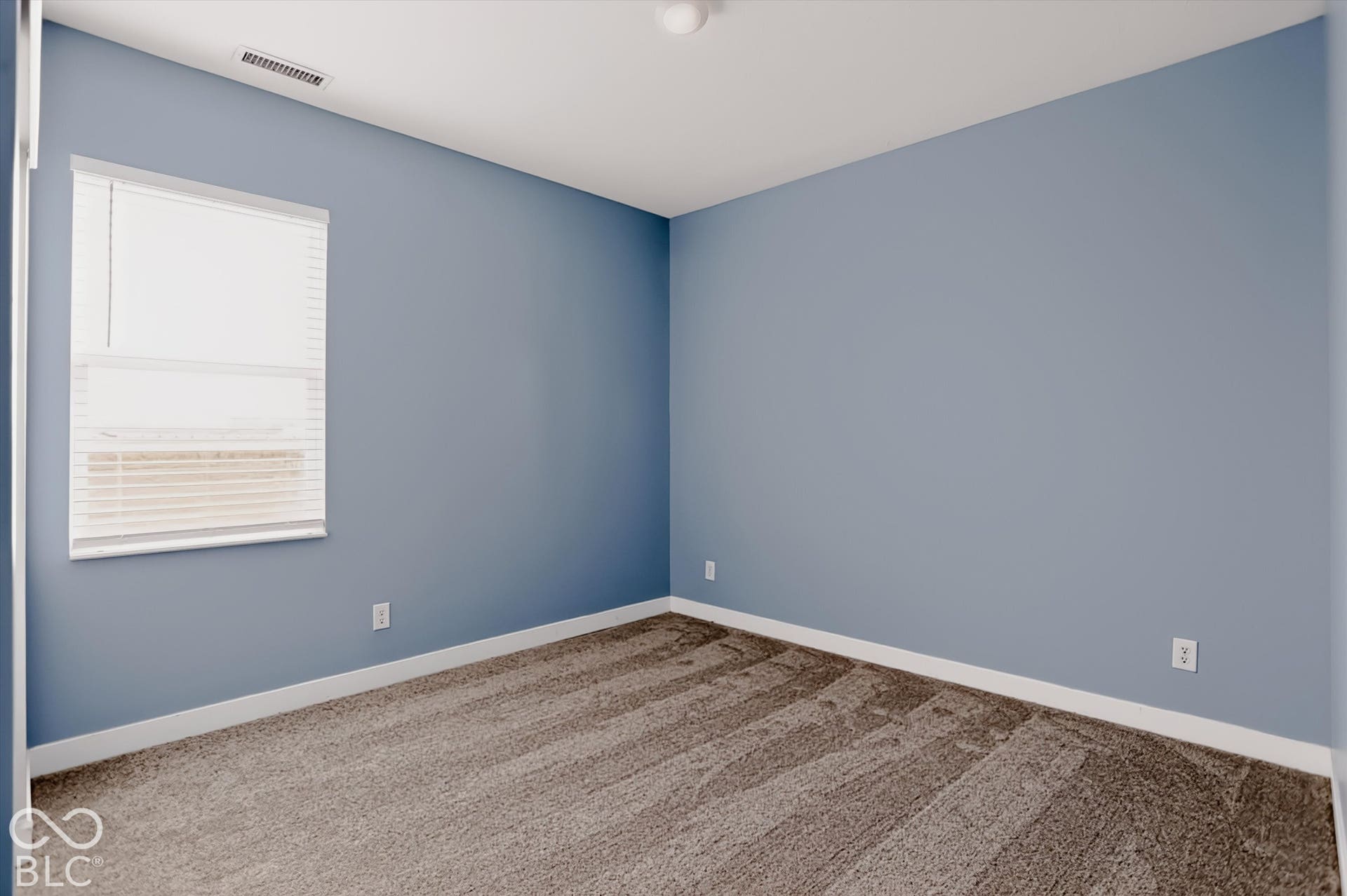 Room featuring wall-to-wall carpeting, dual-tone wall paint, and a single-pane window with installed blinds