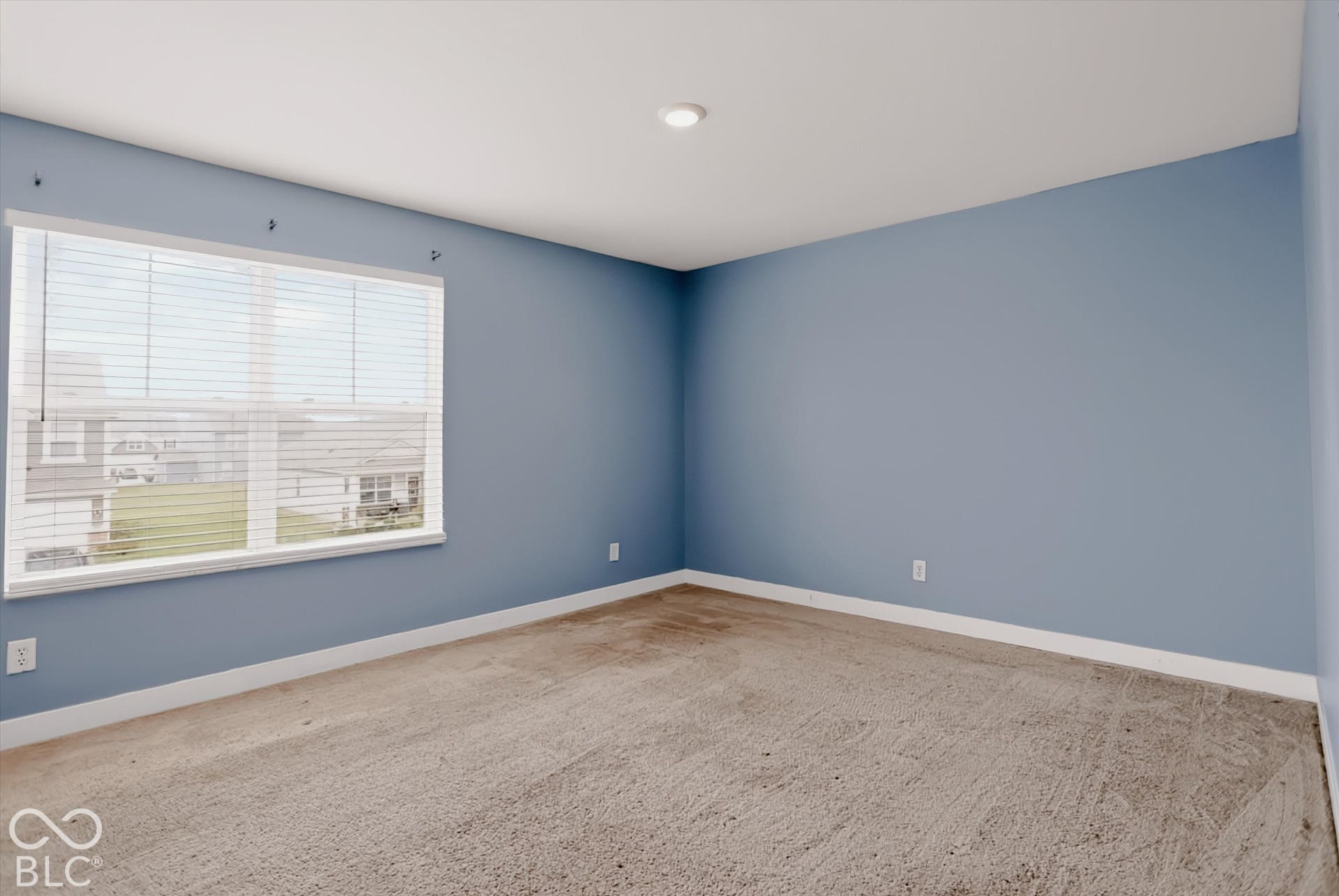 Neutral-toned carpeting, large window with integrated blinds, and recessed lighting