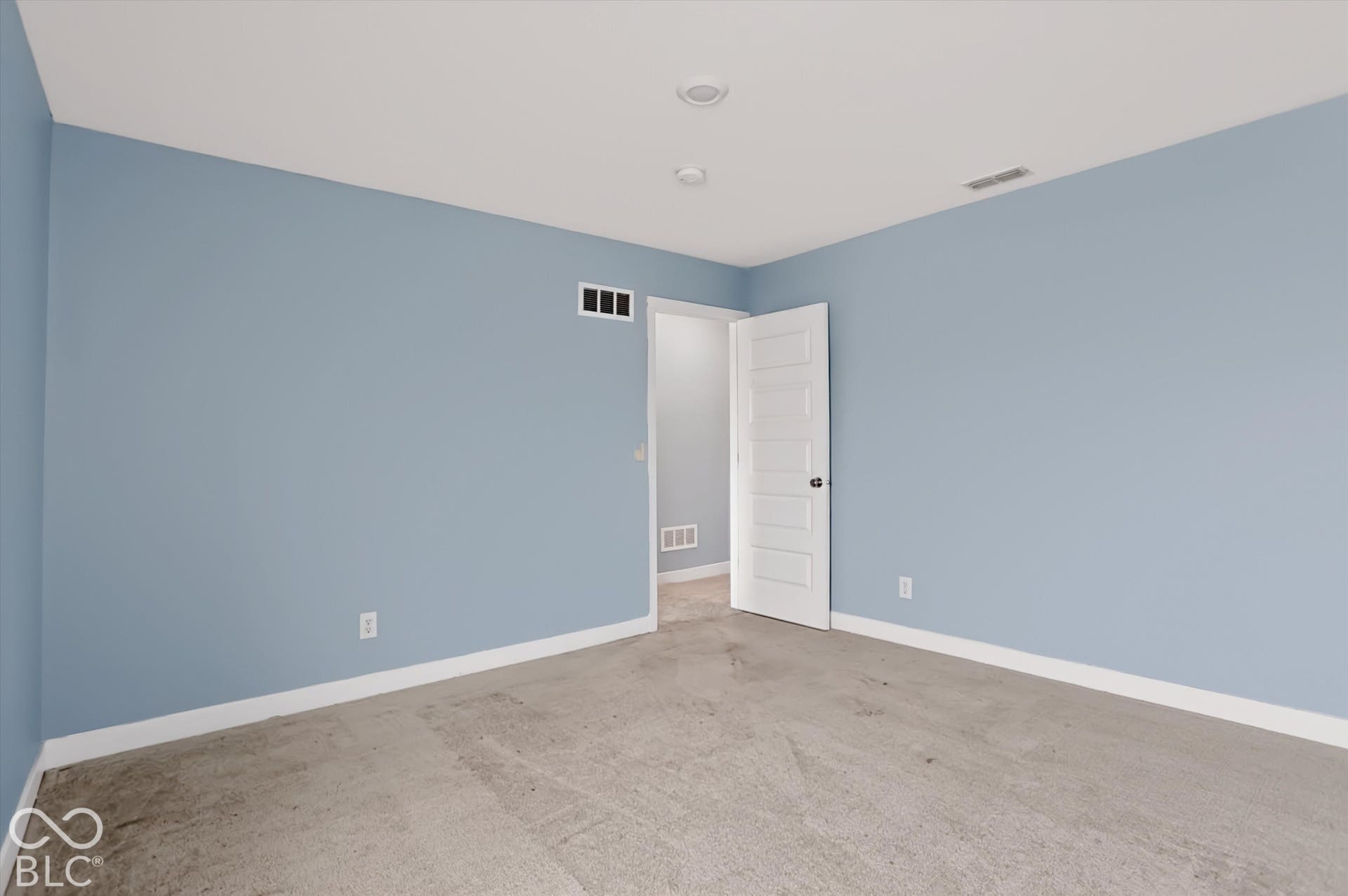 Room featuring neutral carpeting, light blue wall paint, recessed lighting, and a white five-panel interior door