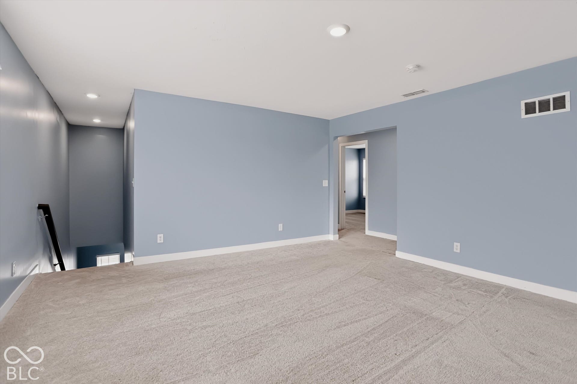 Neutral-toned interior space featuring light-colored wall paint, plush carpeting, and recessed ceiling lighting