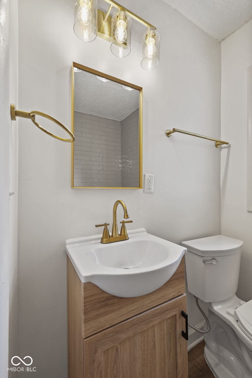 Brushed gold-finish vanity light fixture, framed mirror, and hardware