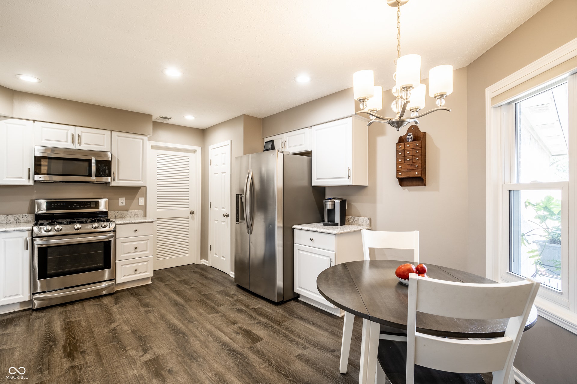 Kitchen featuring stainless steel appliances, white cabinetry, wood-finish flooring, recessed lighting, and a chandelier
