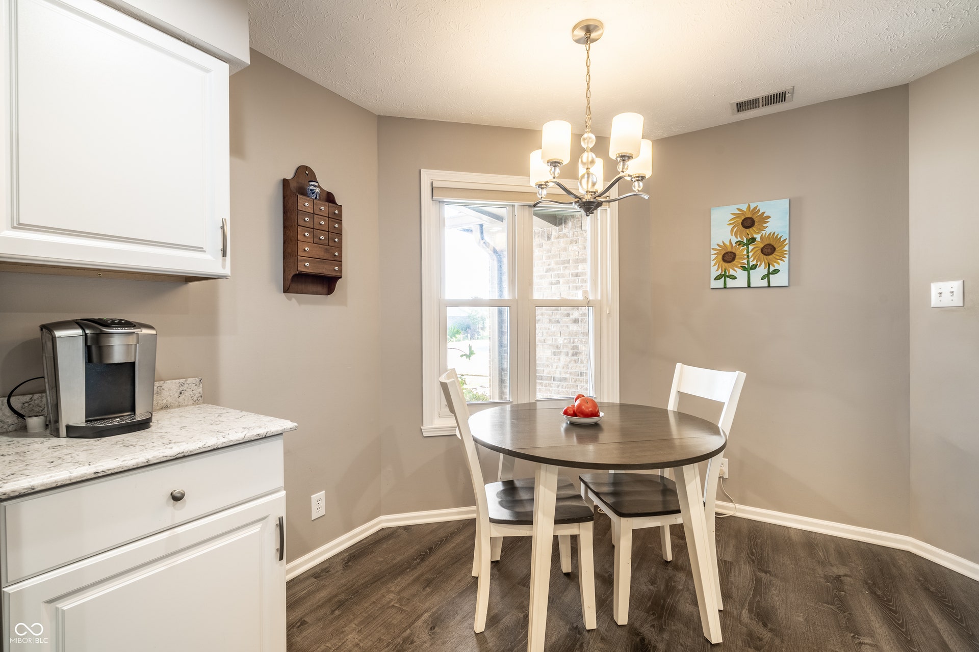 Dining nook with a multi-light chandelier, double-hung window, light-toned wall paint, and wood-finish flooring