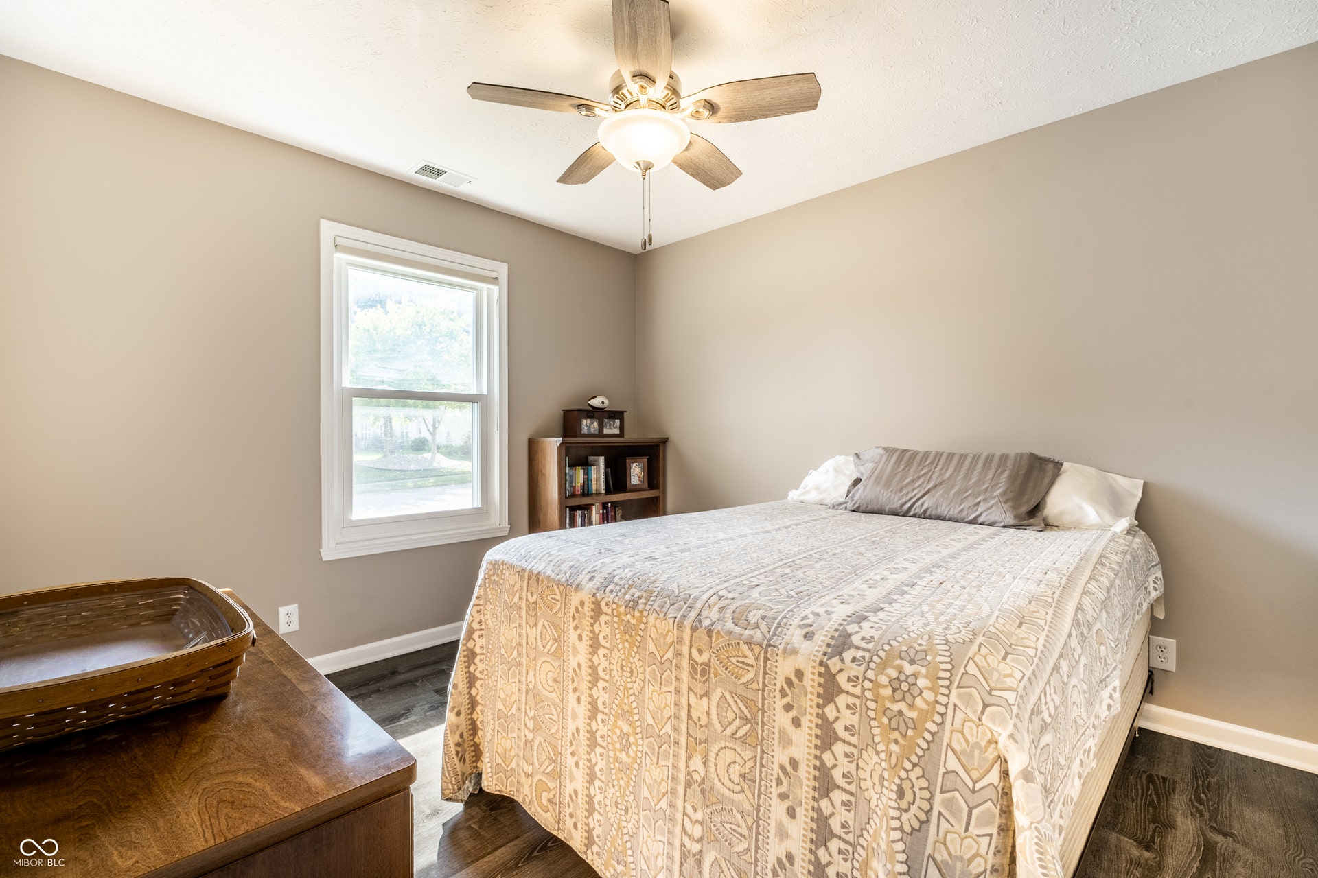 Bedroom #2; East facing window with white trim, wood-finish flooring, ceiling fan with integrated lighting, and neutral wall tones. (Not pictured- walk-in closet)