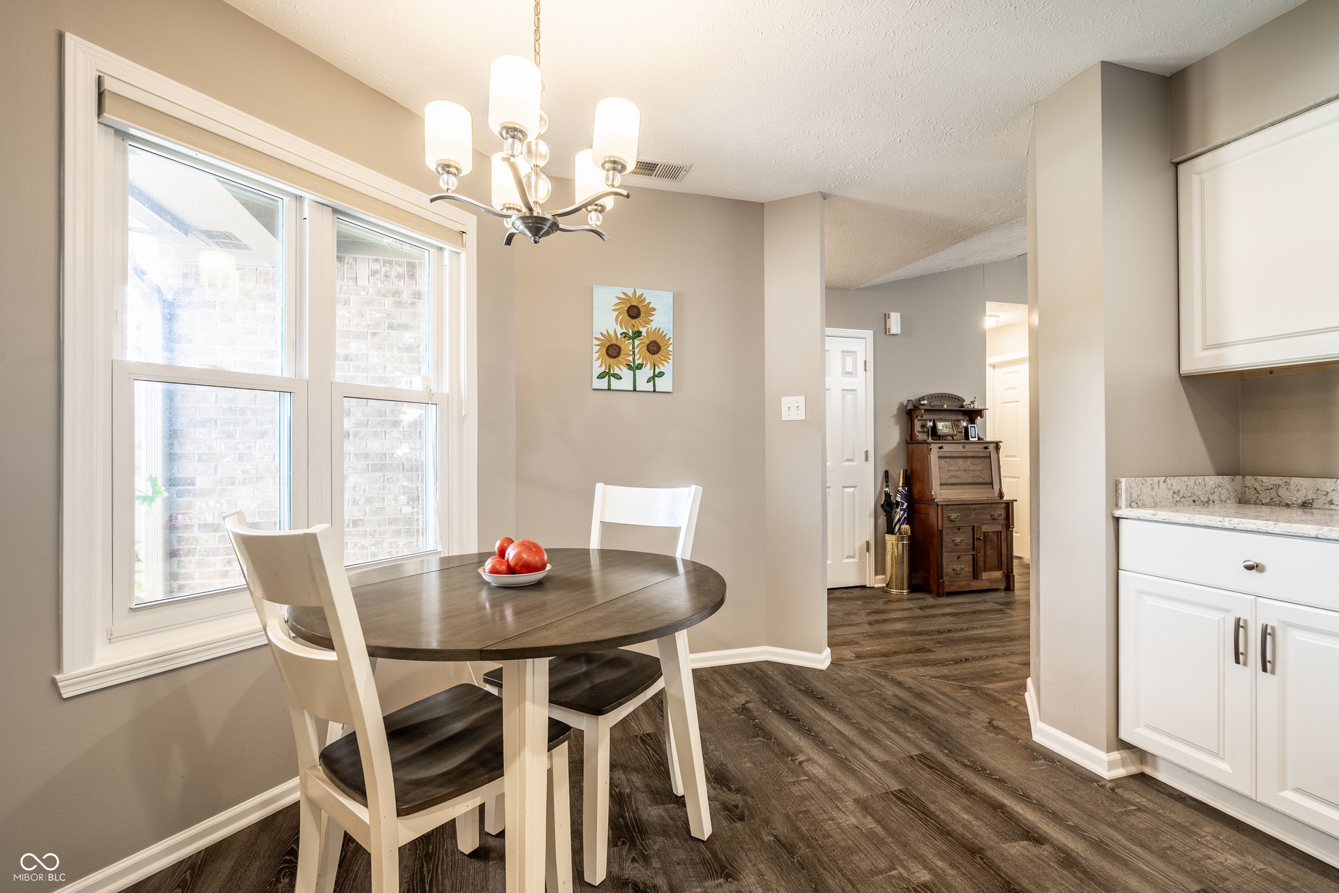 LVP flooring throughout, white cabinetry, quartz countertops, and a modern chandelier