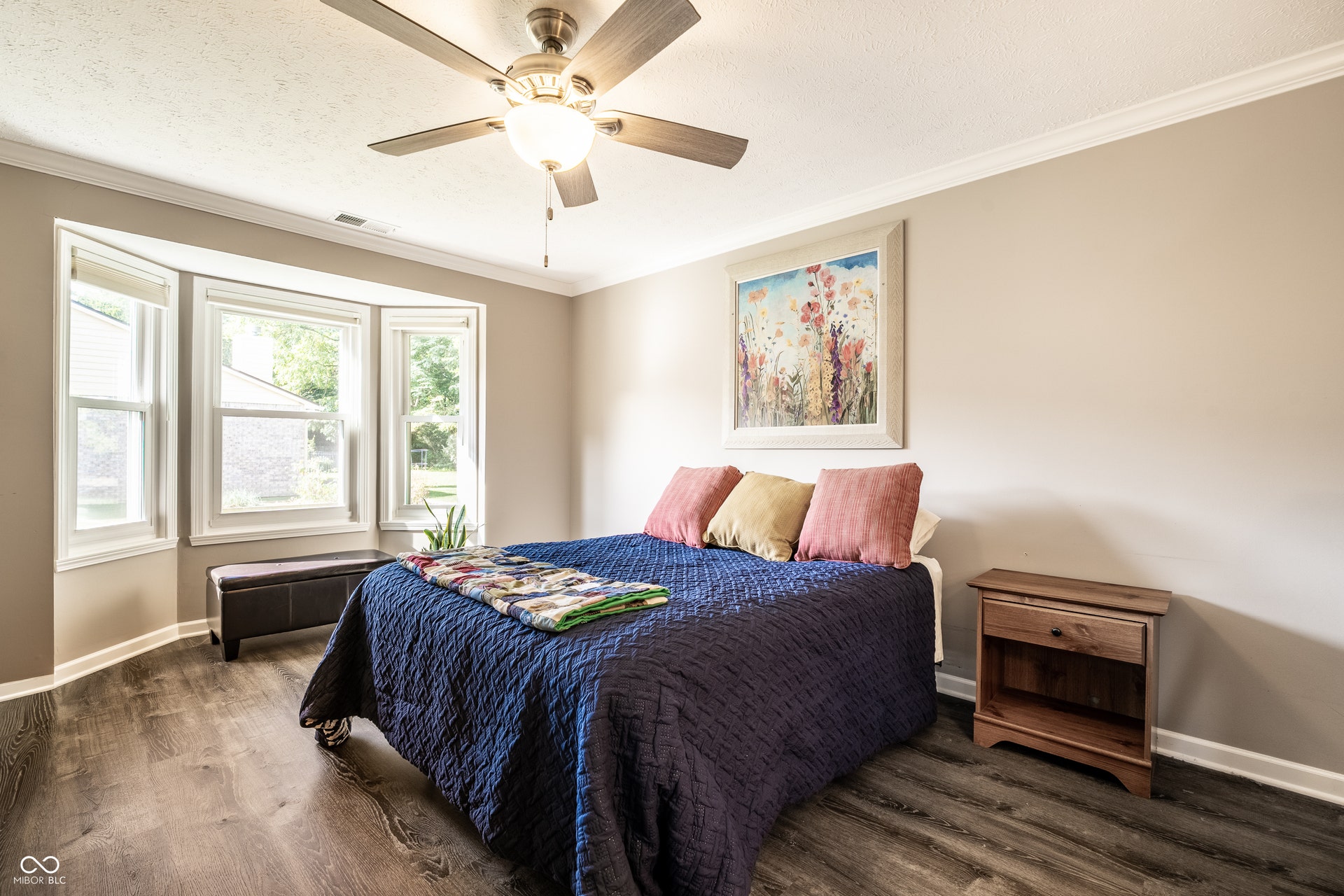 Bay window, ceiling fan with light fixture, crown molding, and wood-finish flooring