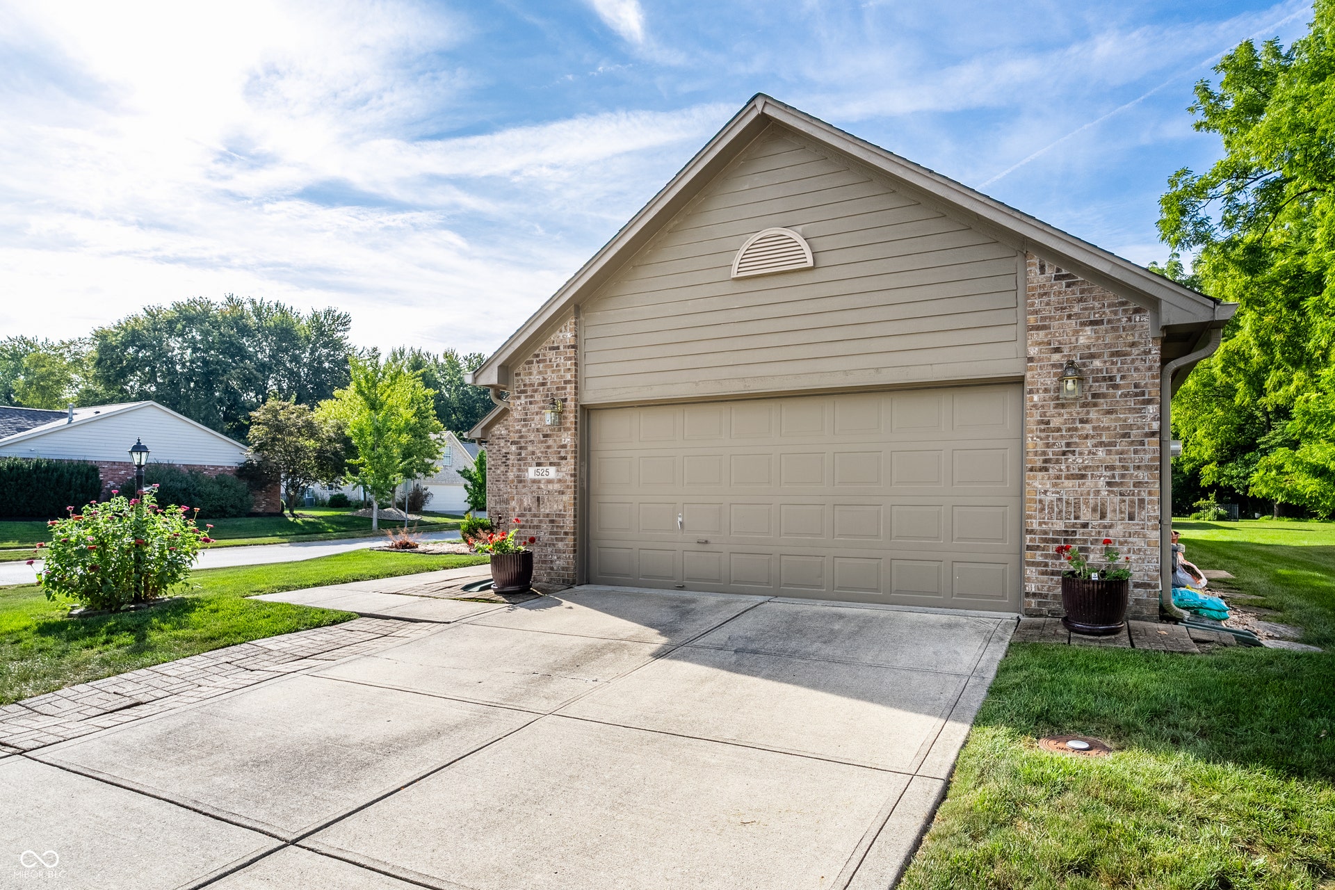 Exterior featuring a two-car garage with side entery door, brick facade accents, and siding