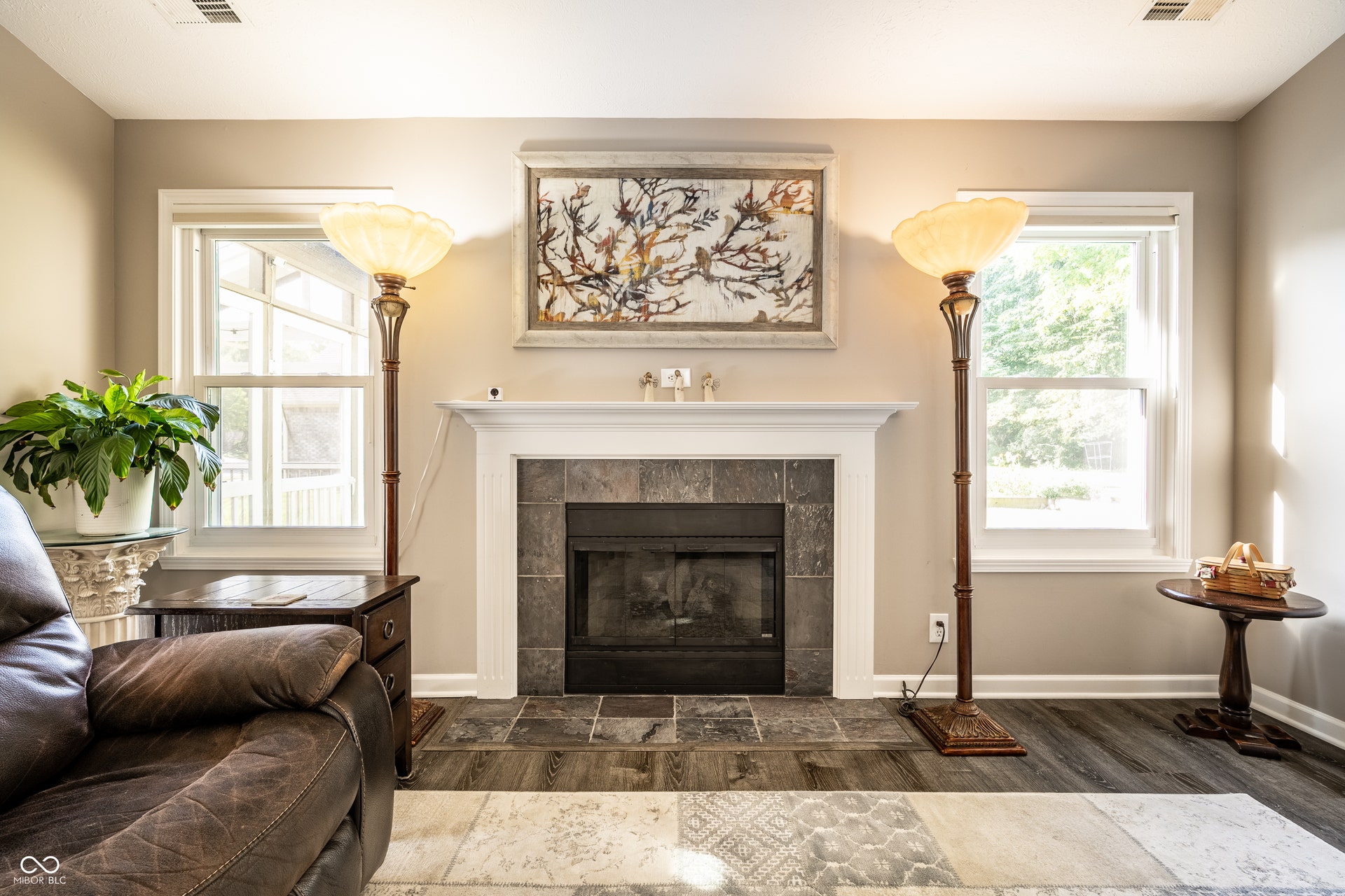 Fireplace with a white mantel and dark slate surround, flanked by two windows