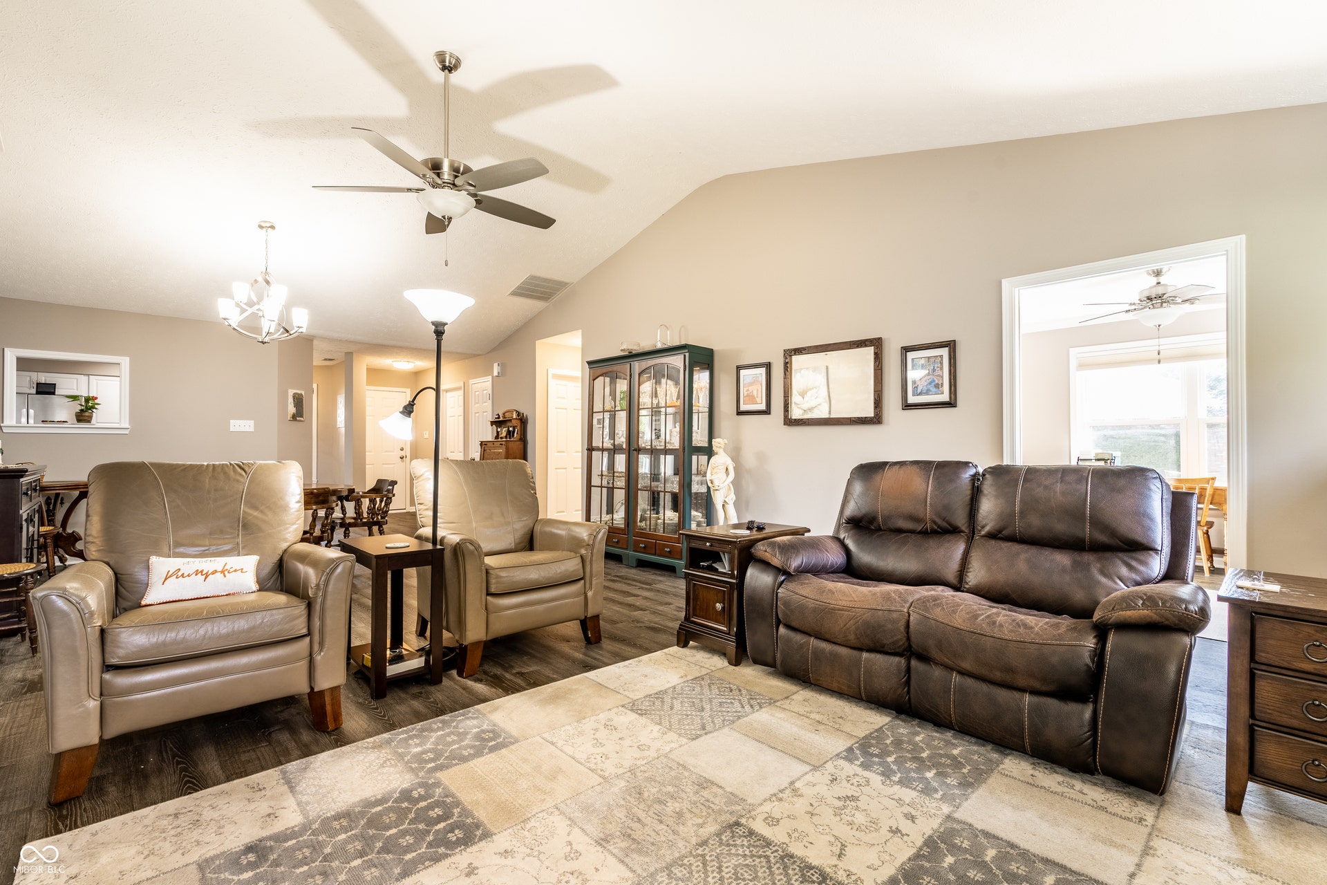 Vaulted ceiling with a ceiling fan, wood-finish flooring, and neutral wall tones