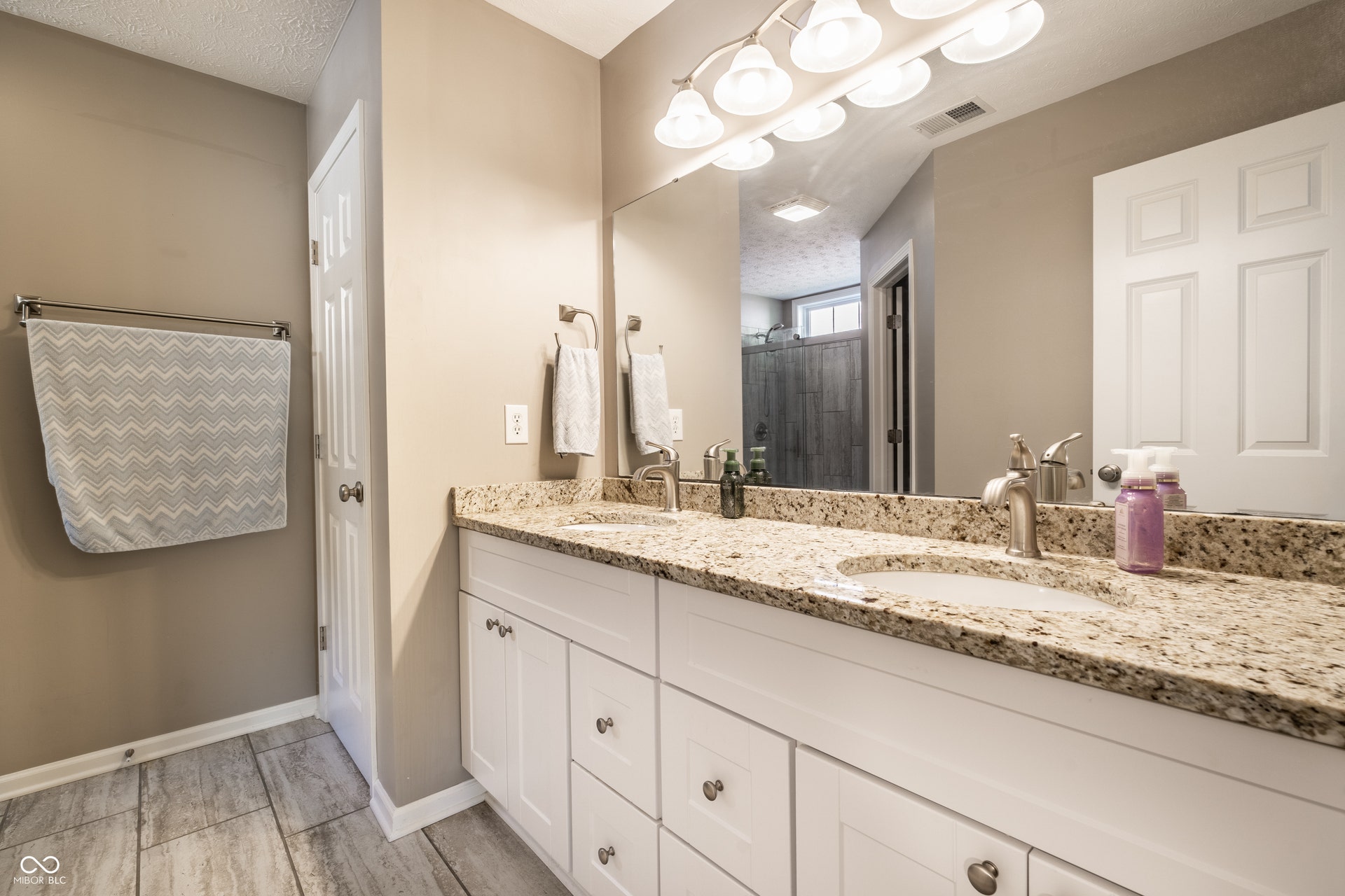 Dual vanity with under-mount sinks, granite countertop, updated light fixtures and white shaker-style cabinetry