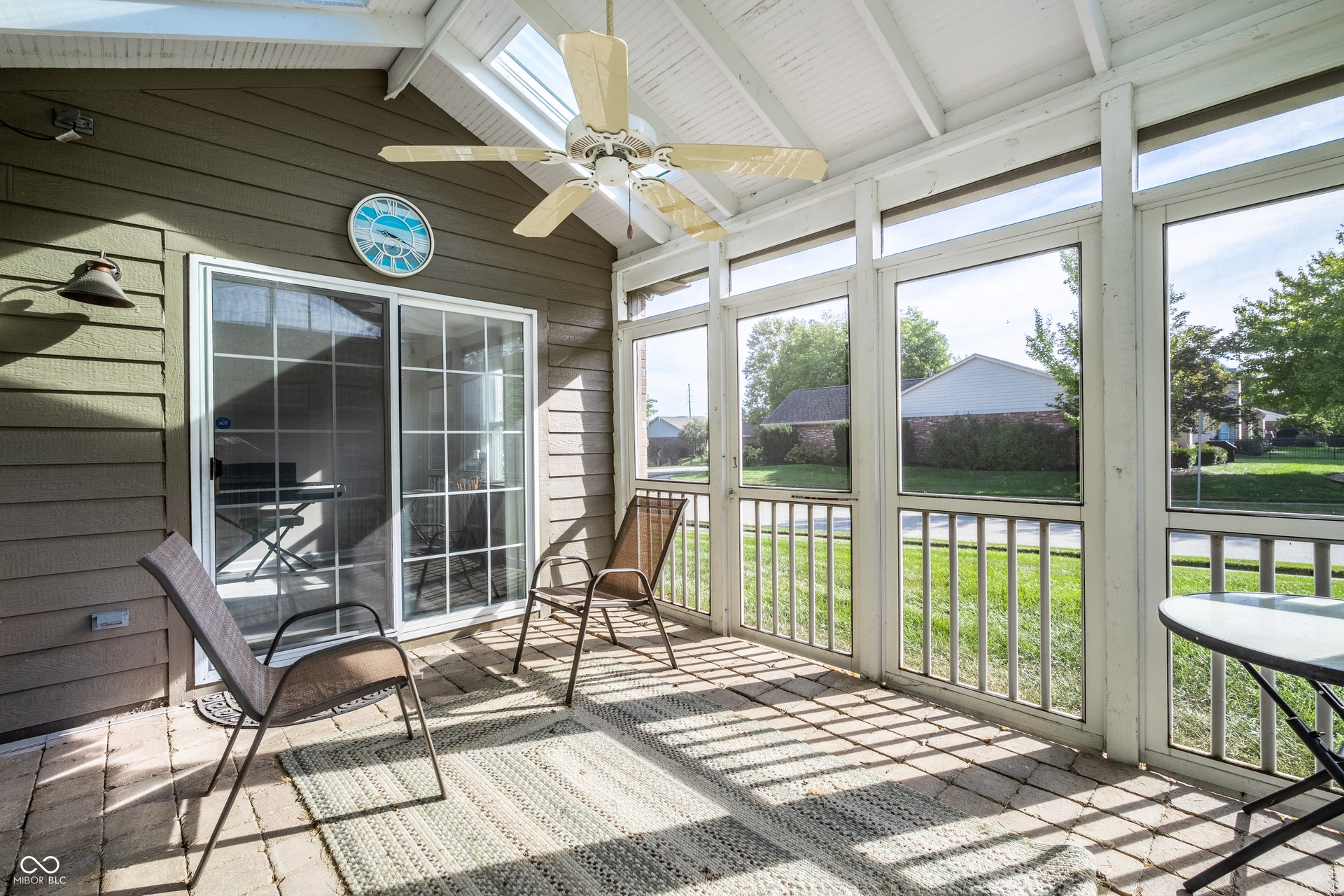 Screened porch featuring a vaulted ceiling with exposed beams, skylight, ceiling fan, and sliding glass door