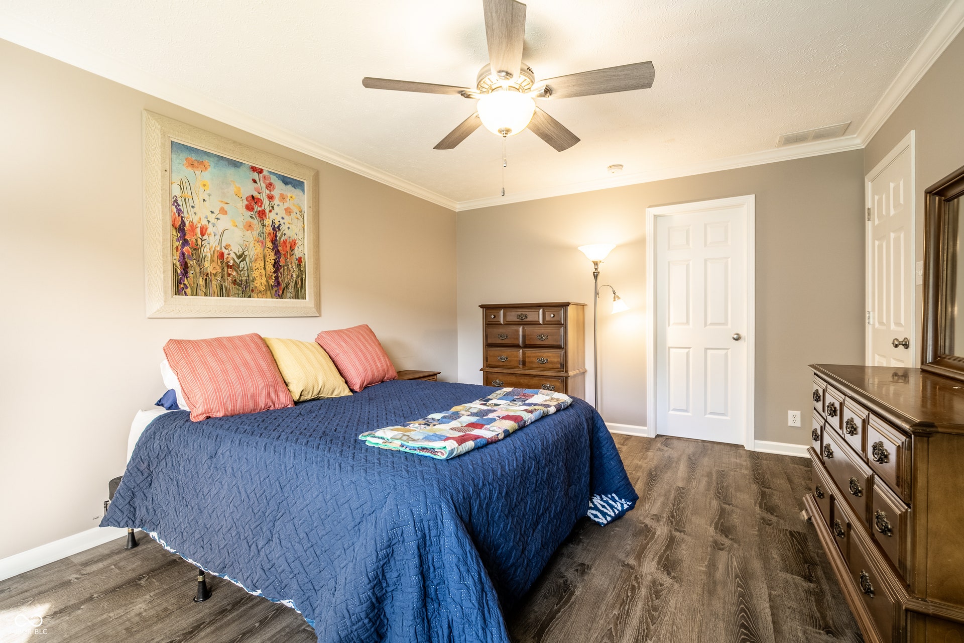 Neutral wall tones, wood-finish flooring, ceiling fan with integrated lighting, crown molding, and white paneled door