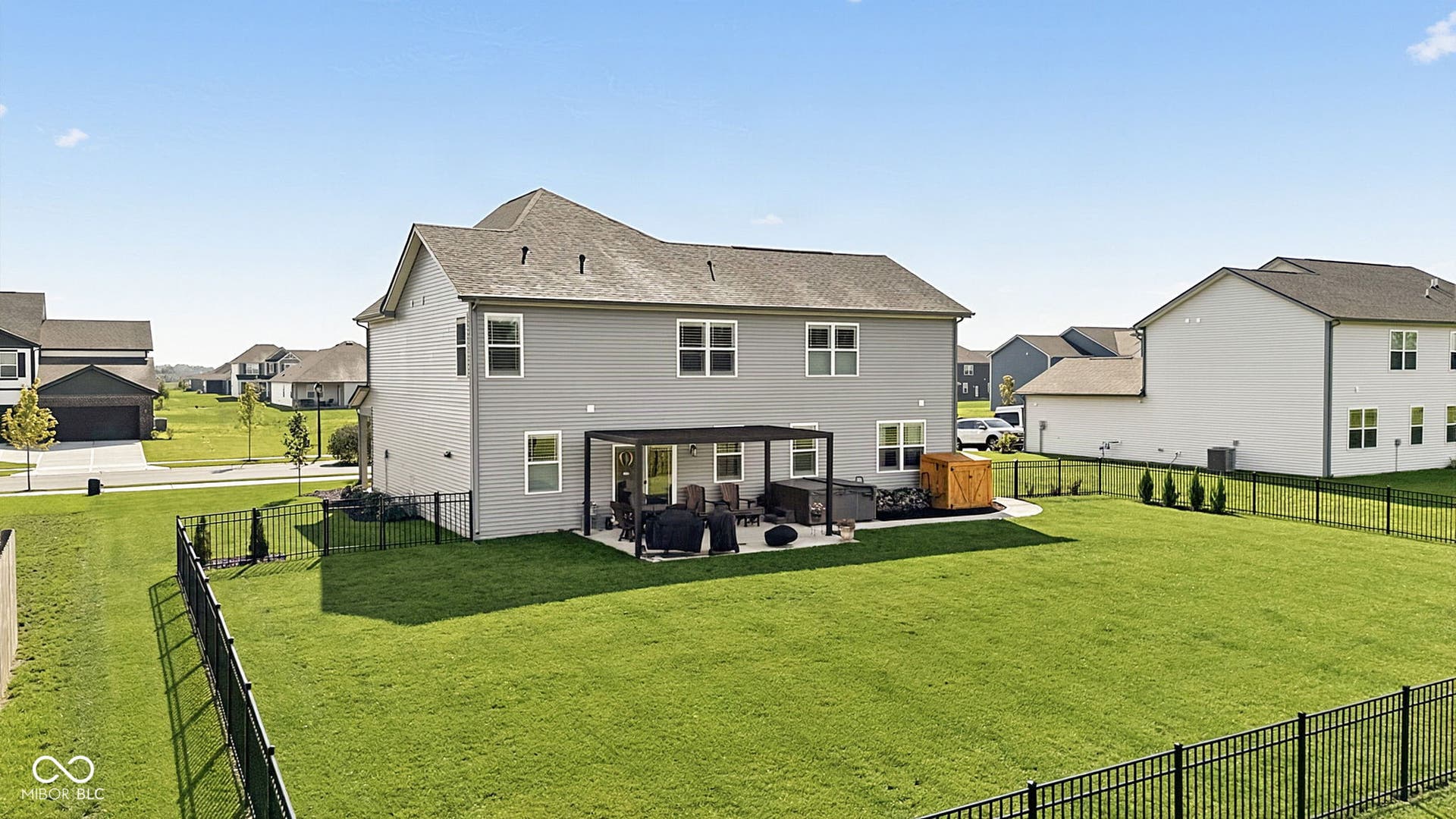 Expansive fenced backyard featuring a stone paver patio, pergola, and established lawn