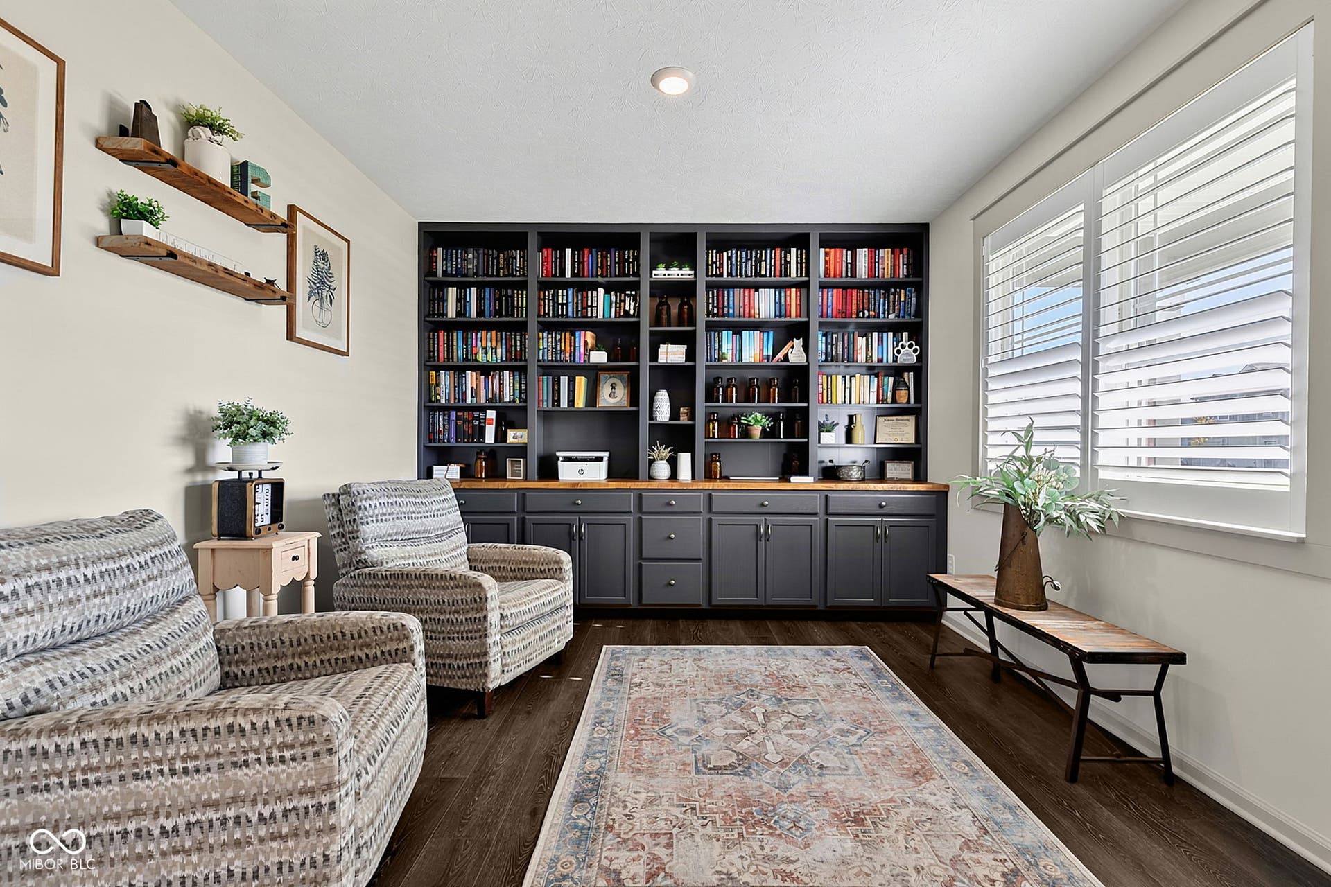 Built-in cabinetry with dark finishes, light wood-finish countertops, wood-finish flooring, and window shutters