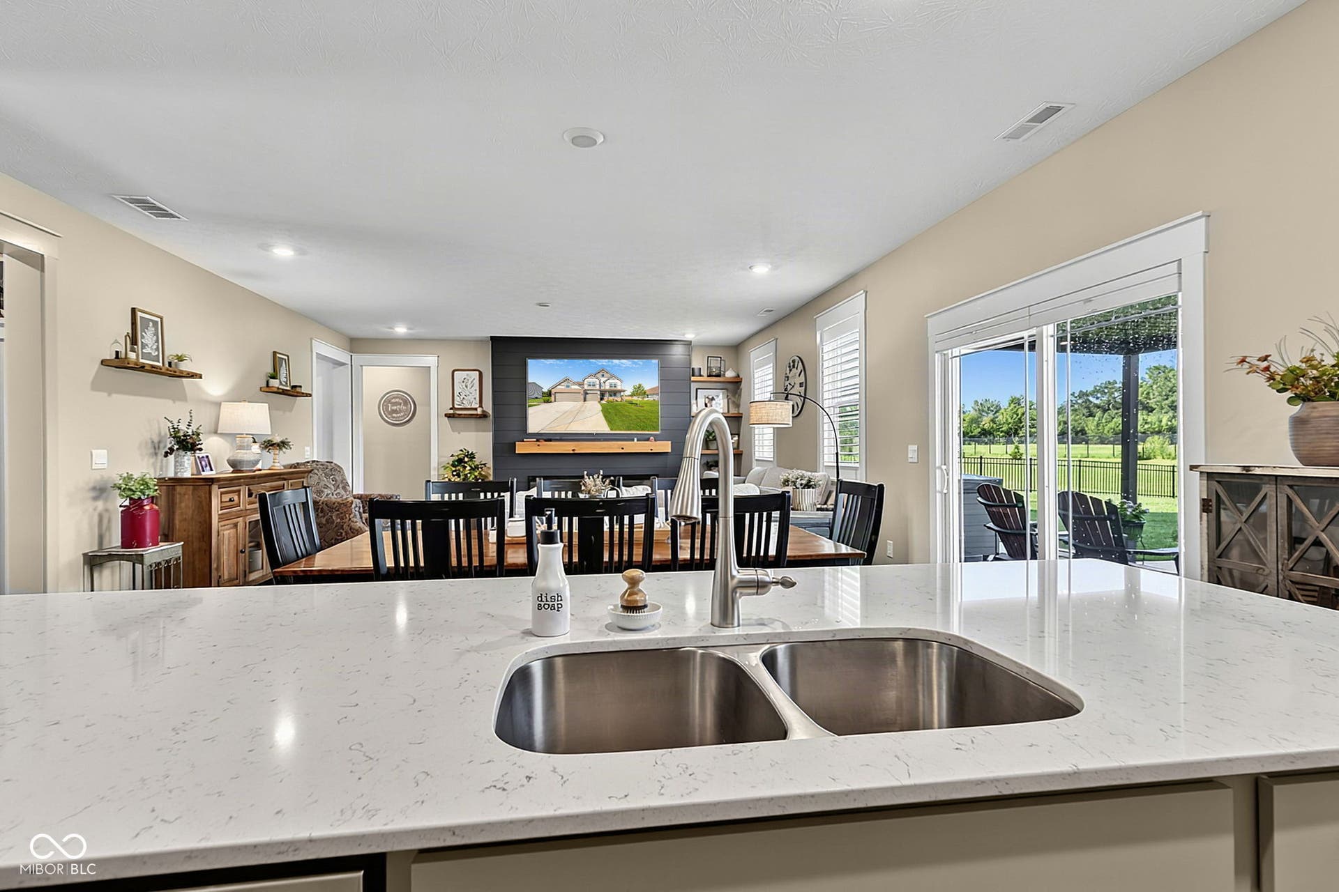 Stainless steel double basin sink with a gooseneck faucet, light-toned countertop, and recessed lighting
