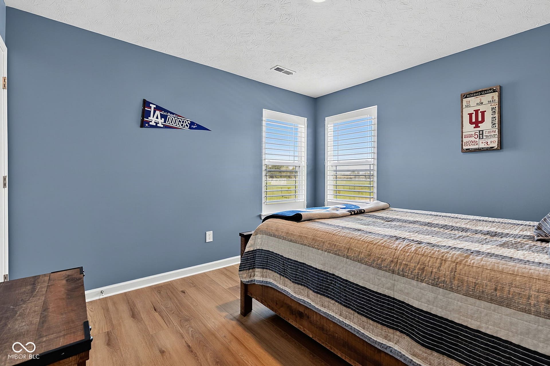 Hardwood-style flooring with white trim, two windows with white blinds, and a built-in ceiling light