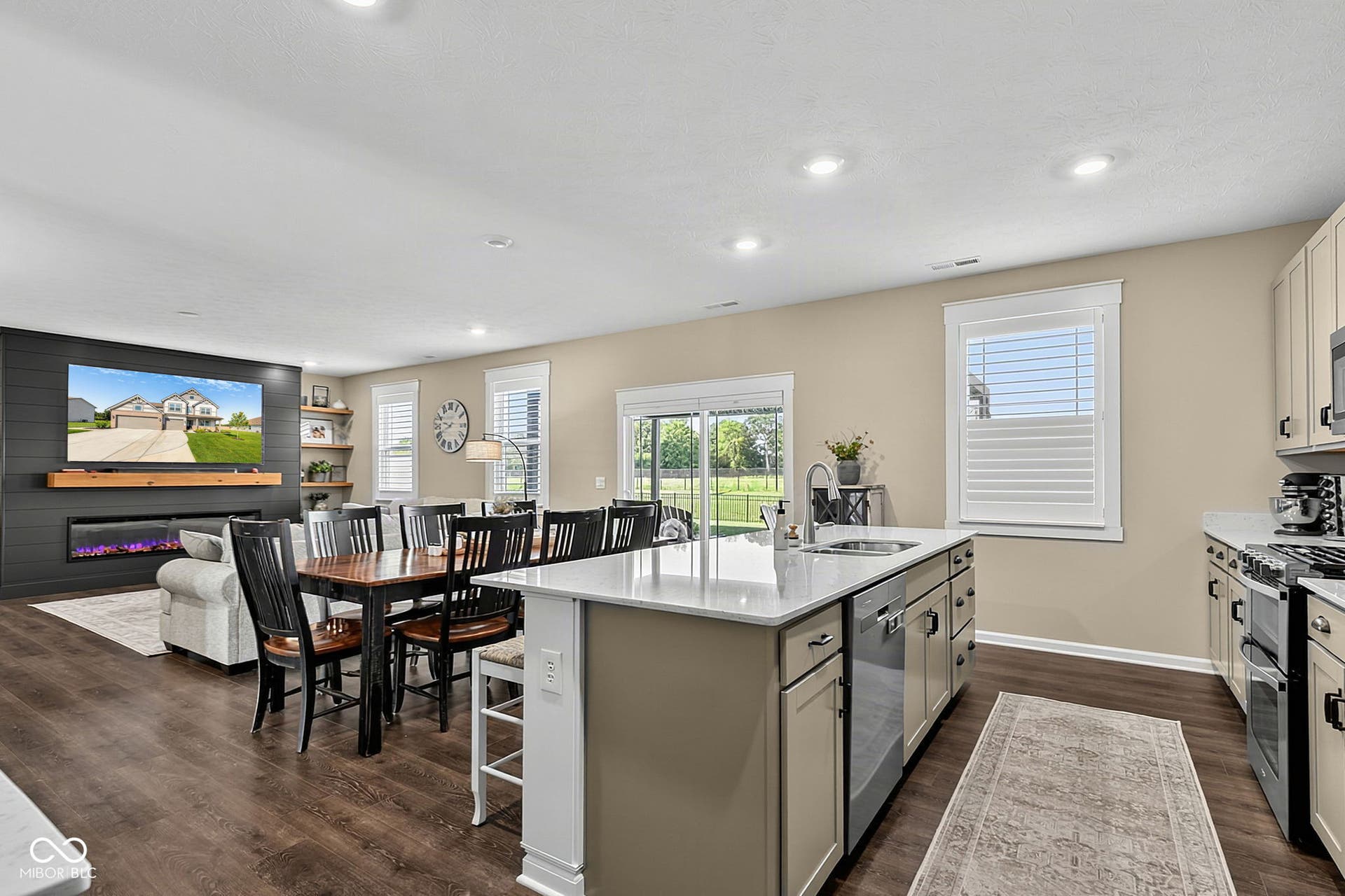 Open-concept living space with wood-finish flooring, a contemporary fireplace with a wood mantle, and built-in shelving