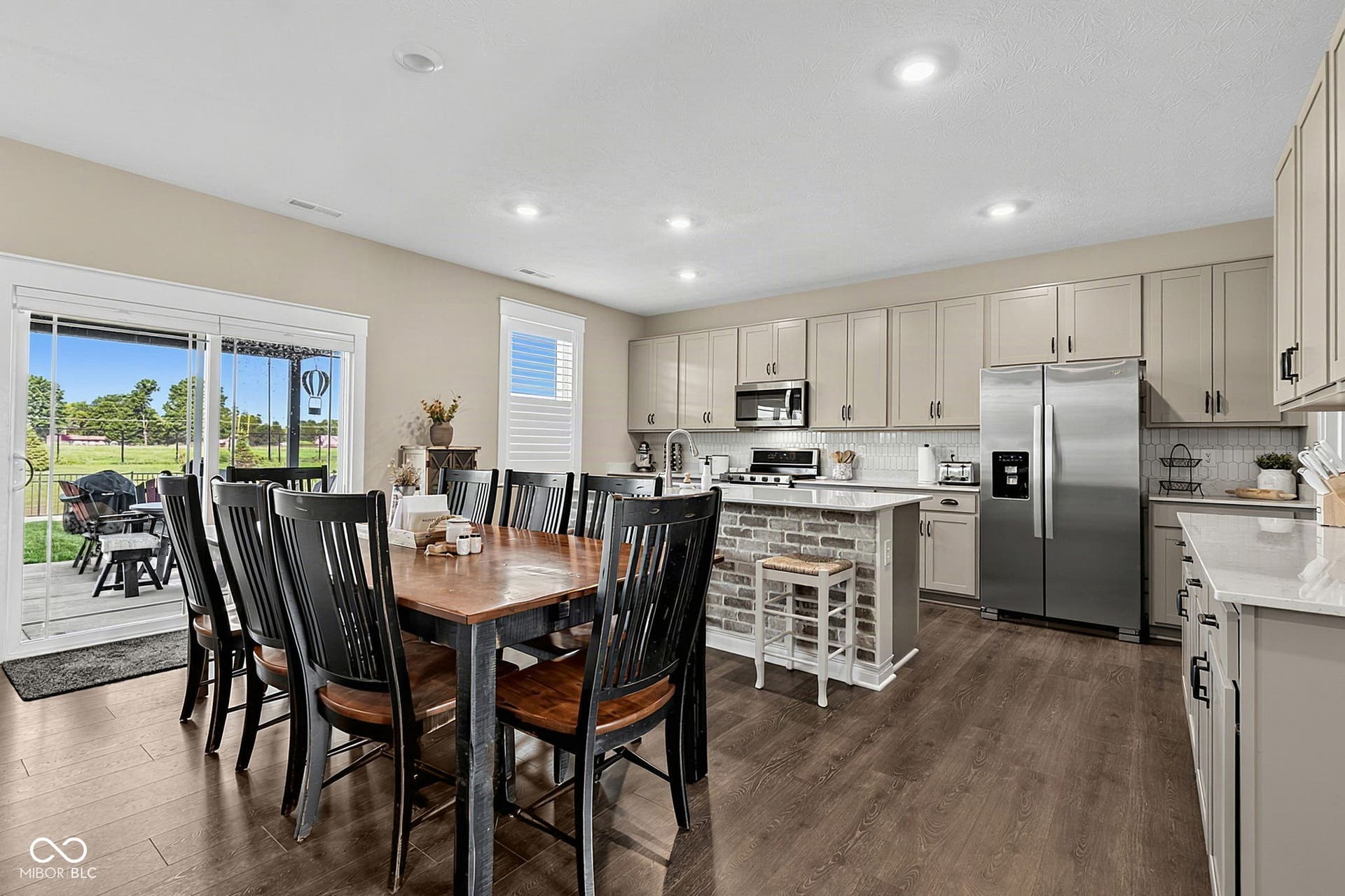 Kitchen featuring wood-finish flooring, recessed lighting, stainless steel appliances, and a brick-accented island with white countertops