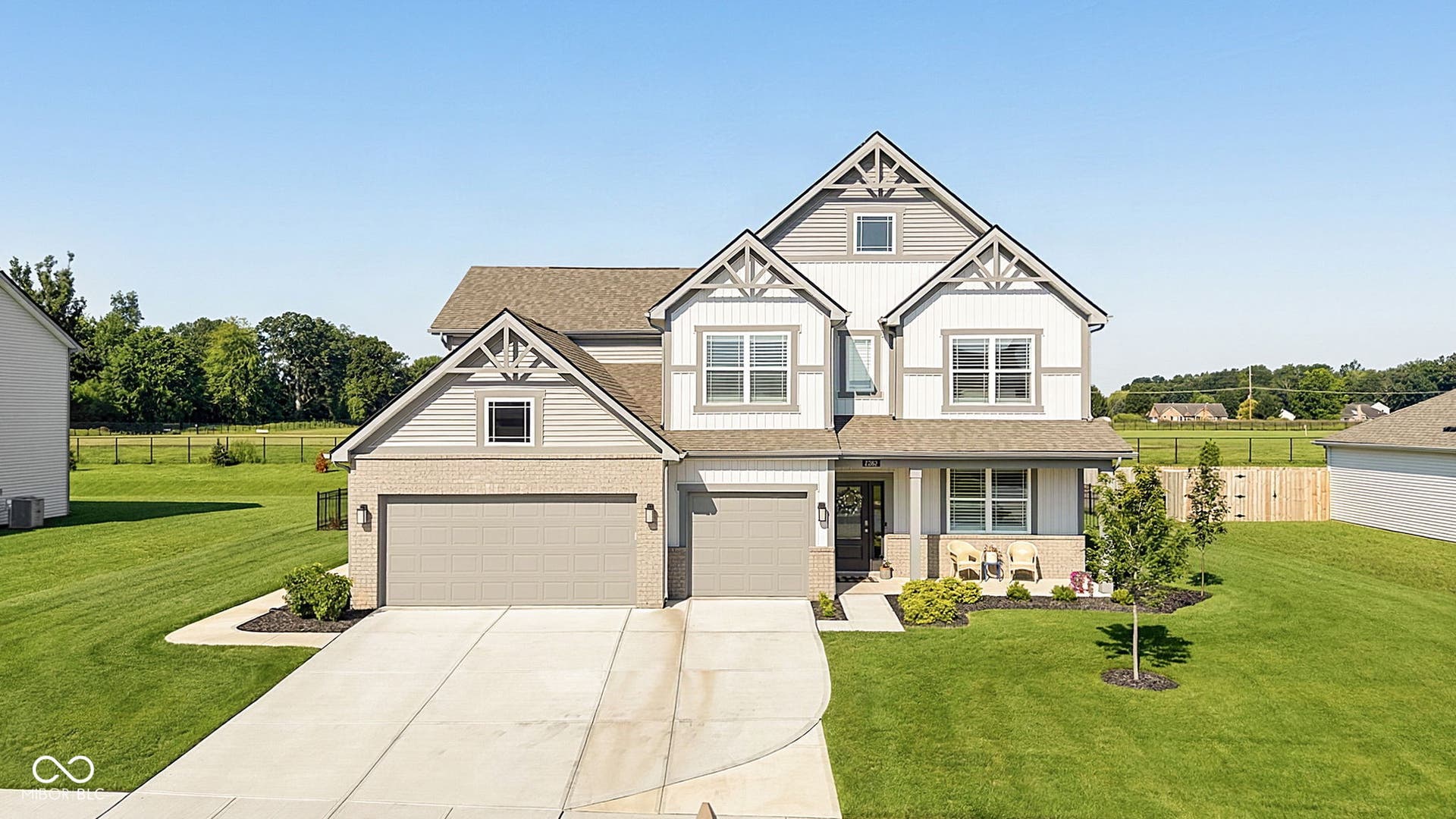 Two-story residence featuring a dual-tone exterior with brick and siding, a two-car garage, multiple gables with decorative brackets, and a covered front porch