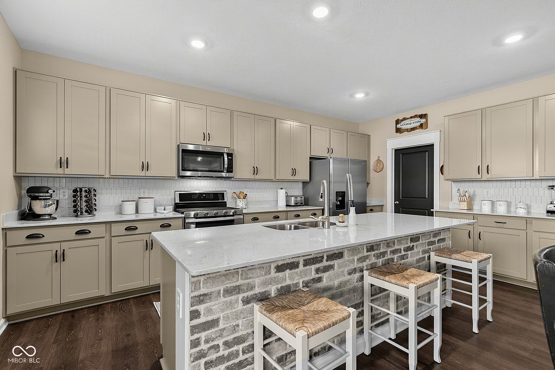Kitchen featuring a spacious island with brick-finish detailing, stainless steel appliances, extensive cabinetry, a tile backsplash, and recessed lighting