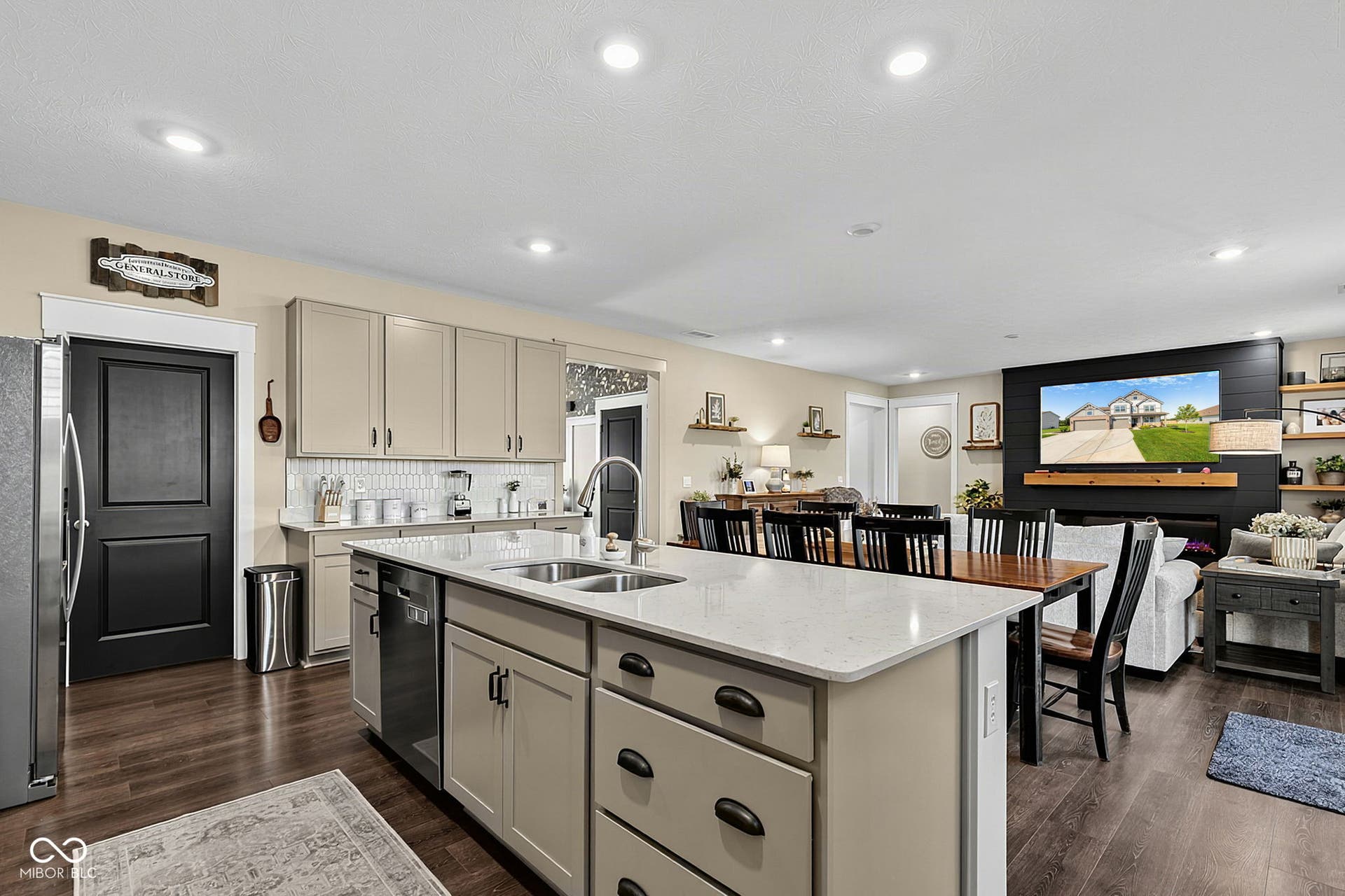Spacious kitchen island with dual sinks, light-toned cabinetry, stainless steel appliances, wood-finish flooring, and recessed lighting