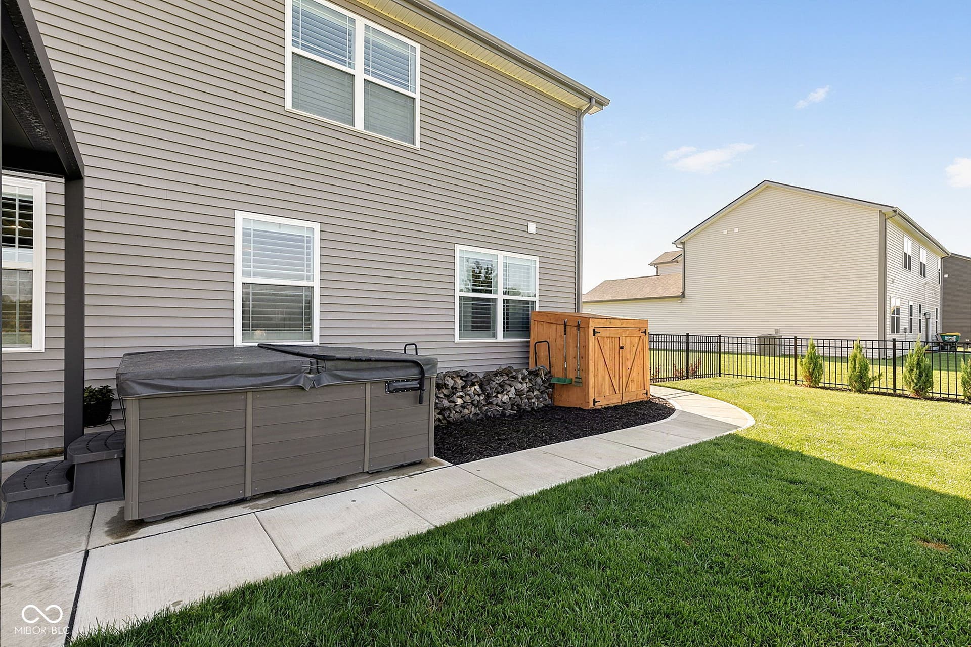 Lawn area featuring a hot tub with cover, curved concrete pathway, and decorative wood storage shed