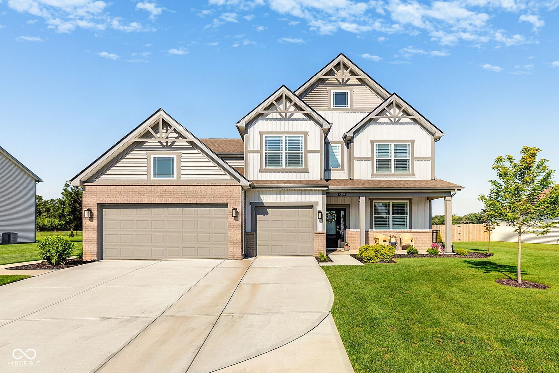 Two-story residence featuring a combination of brick and siding, a covered front entry, and a two-car garage