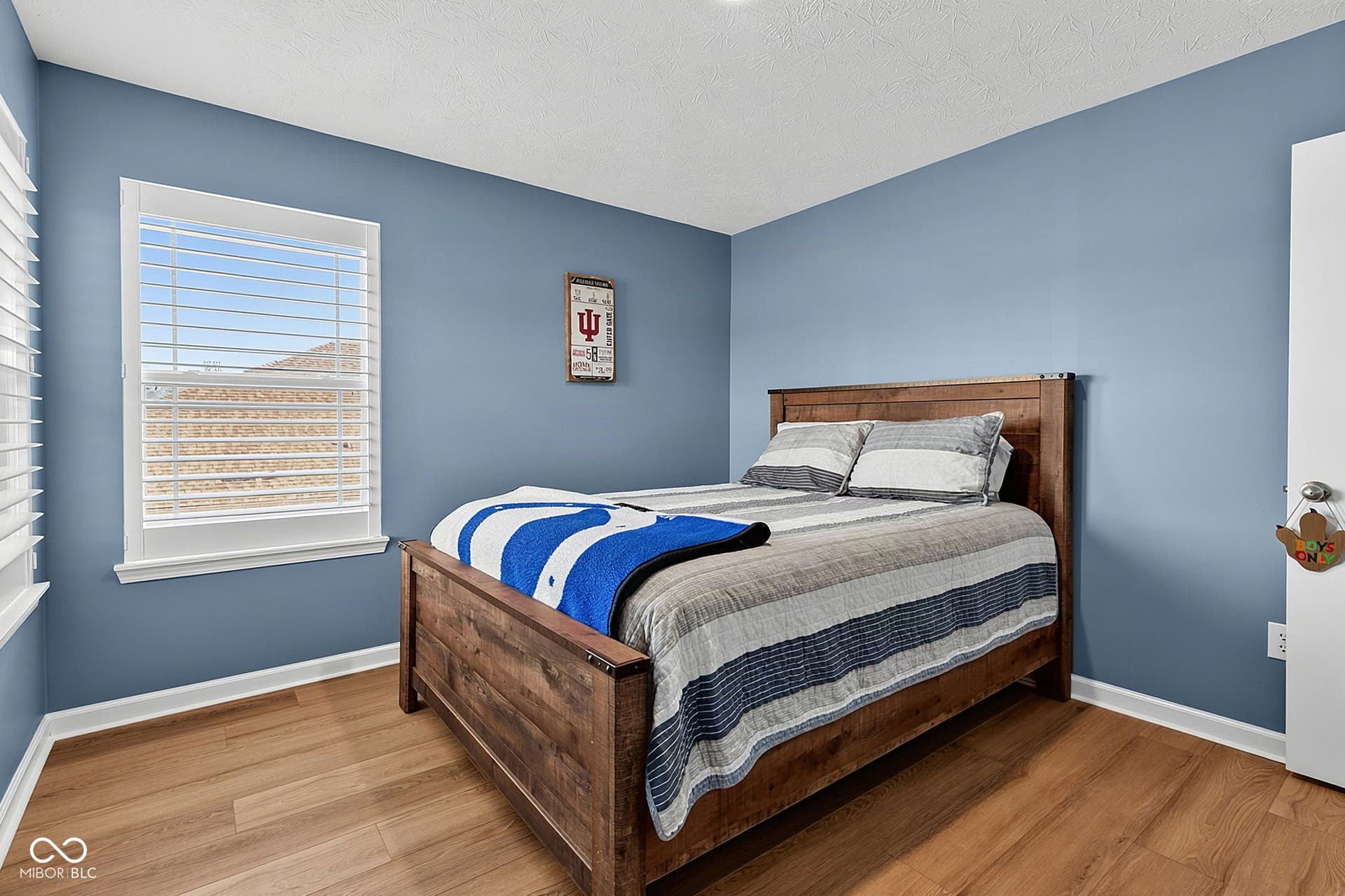 Light blue walls with white trim, wood-finish flooring, and white window blinds