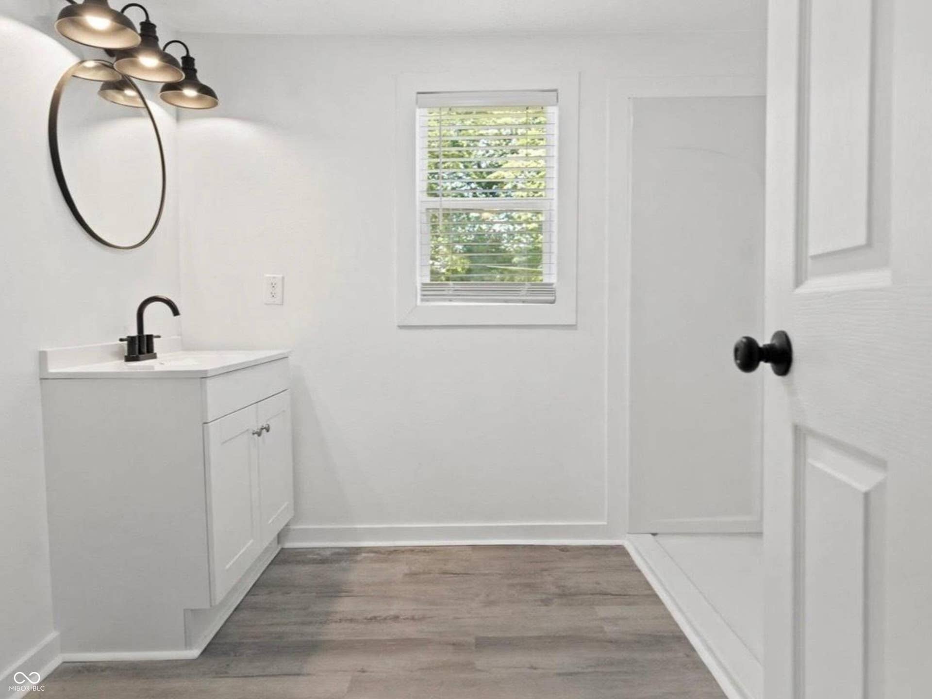 White vanity with integrated sink, matte black faucet, and coordinating hardware