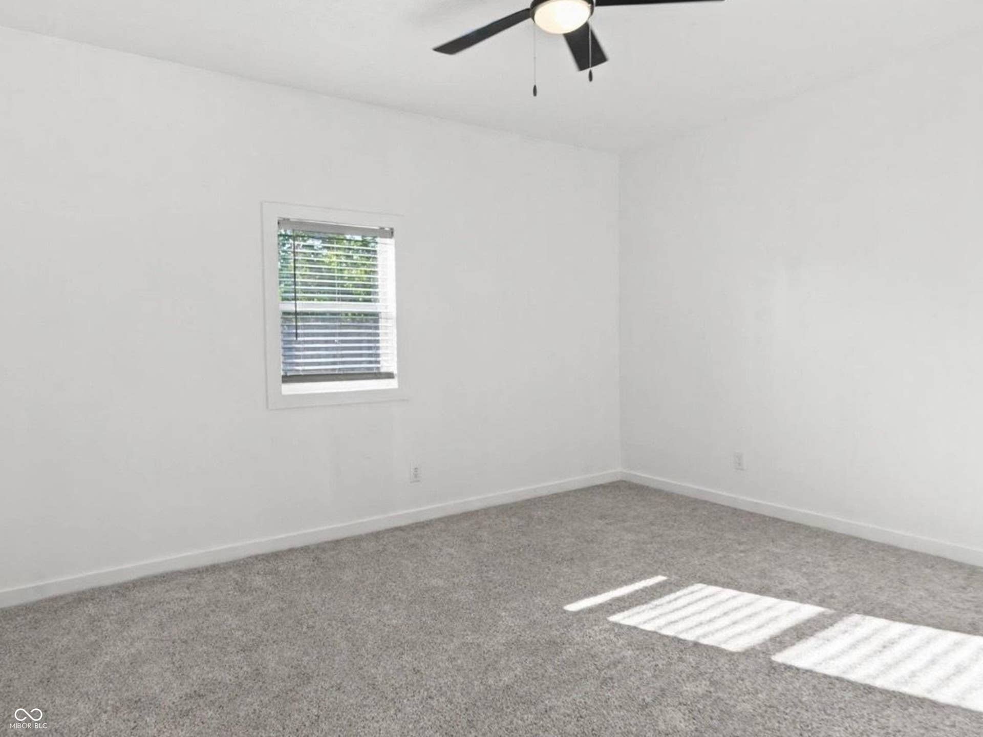 White painted walls, gray carpeting, a window with blinds, and a ceiling fan with integrated lighting
