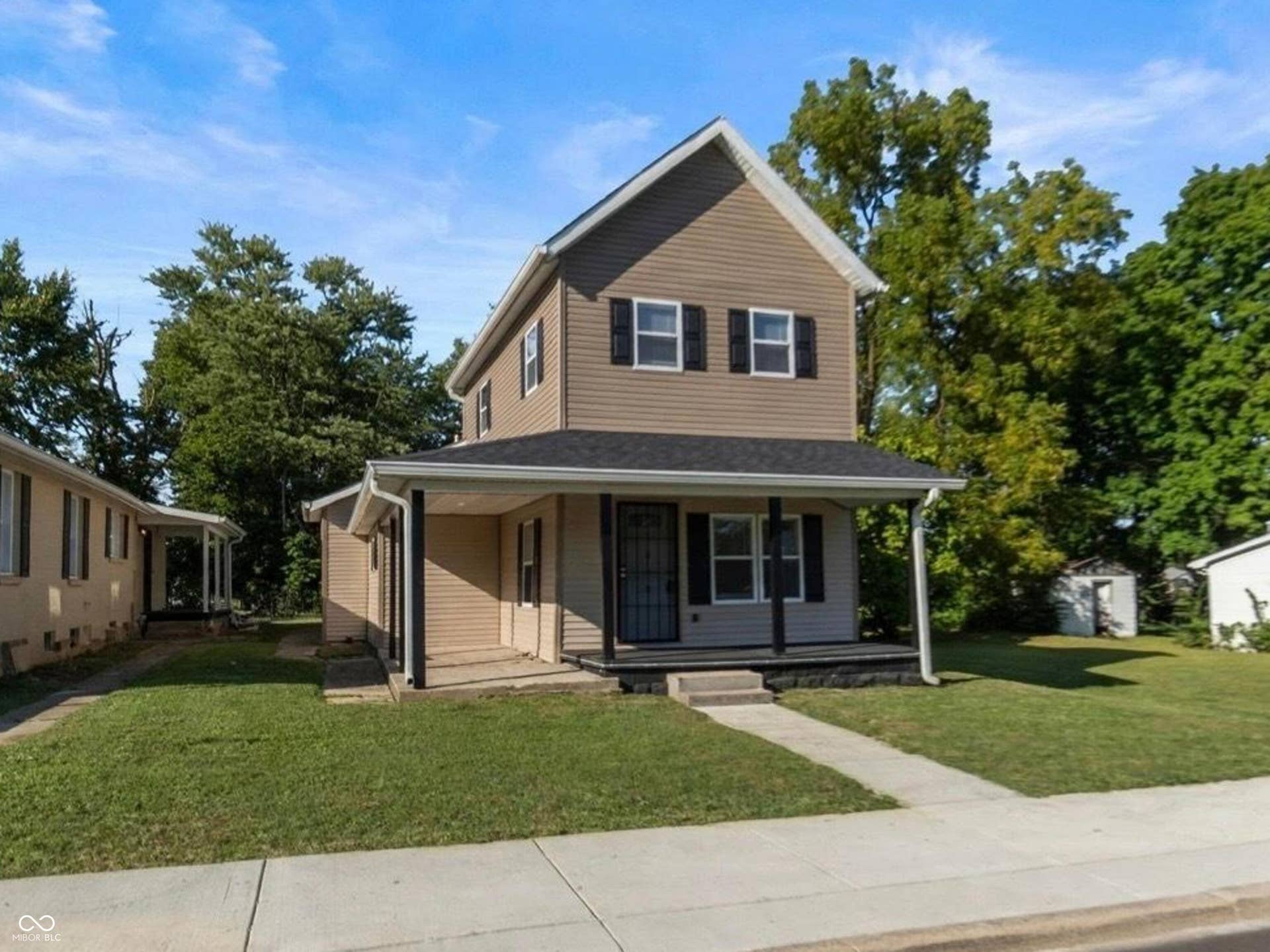 Two-story property with a covered porch, dark shutters, and a front walkway
