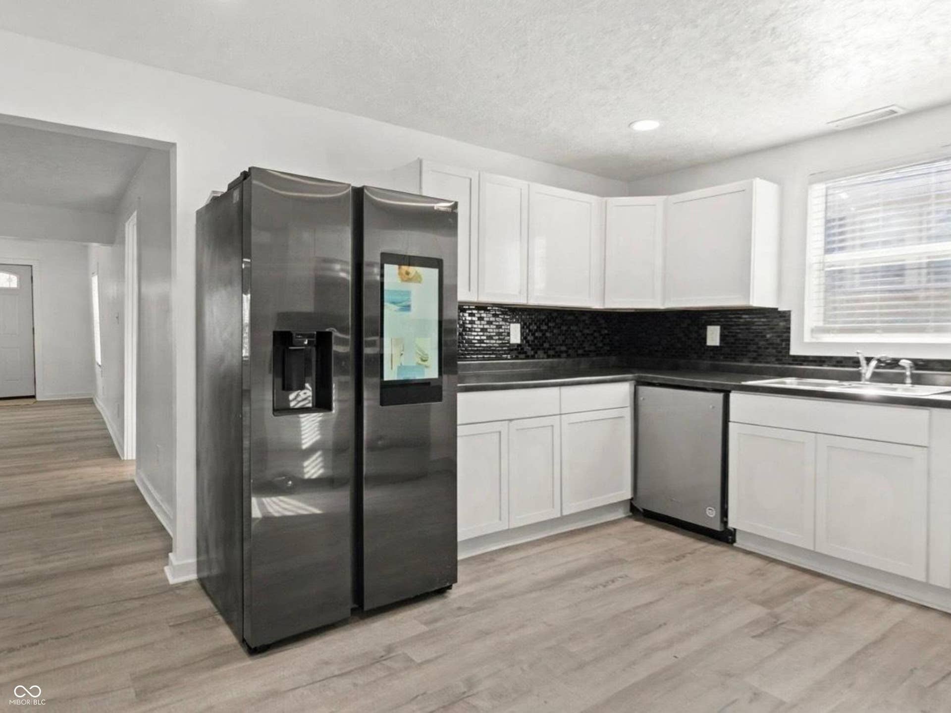 White cabinetry with stainless steel appliances, dark countertops, and a black mosaic tile backsplash