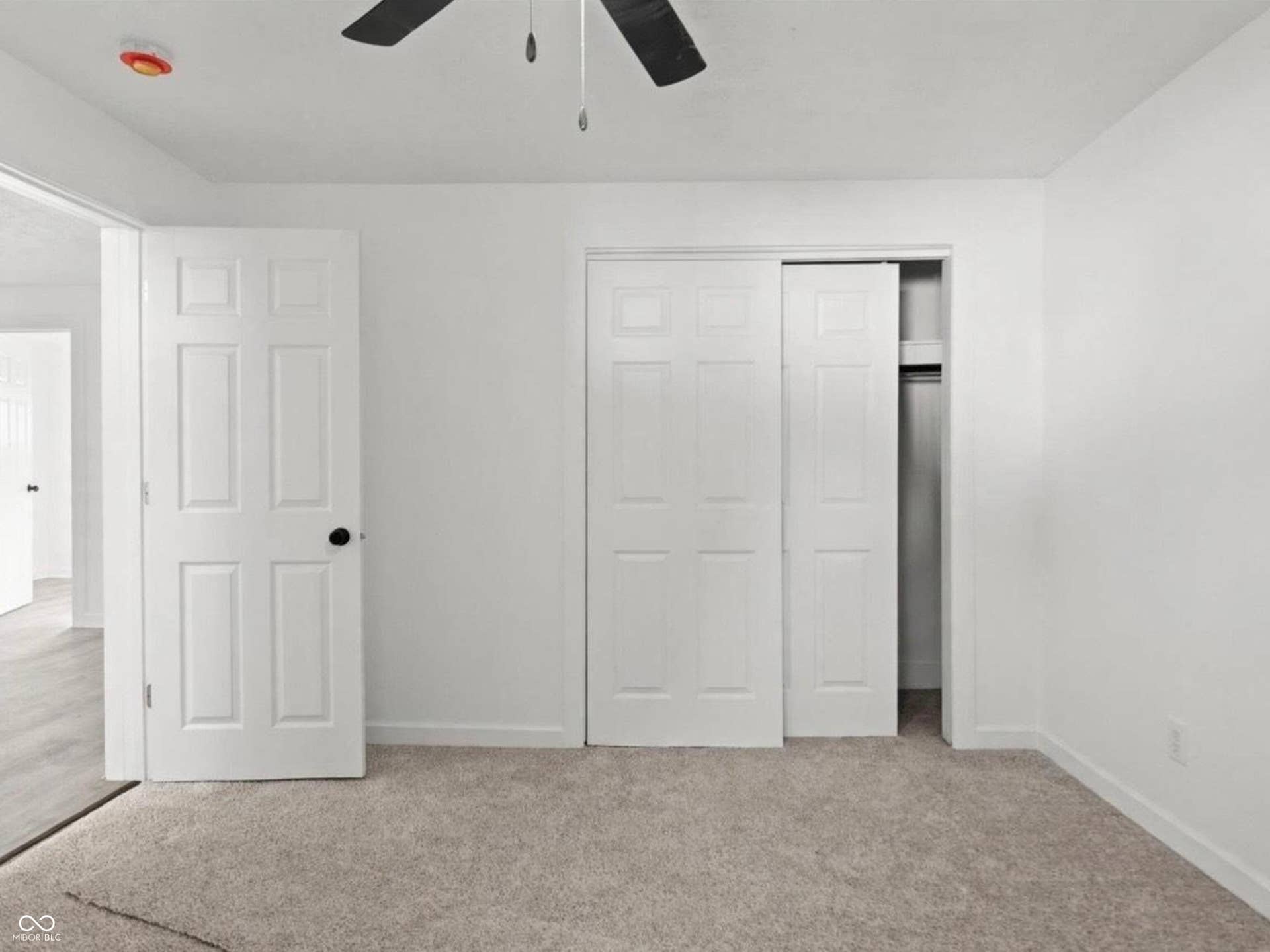 Neutral-toned carpeting, white walls, and a ceiling fan with integrated lighting